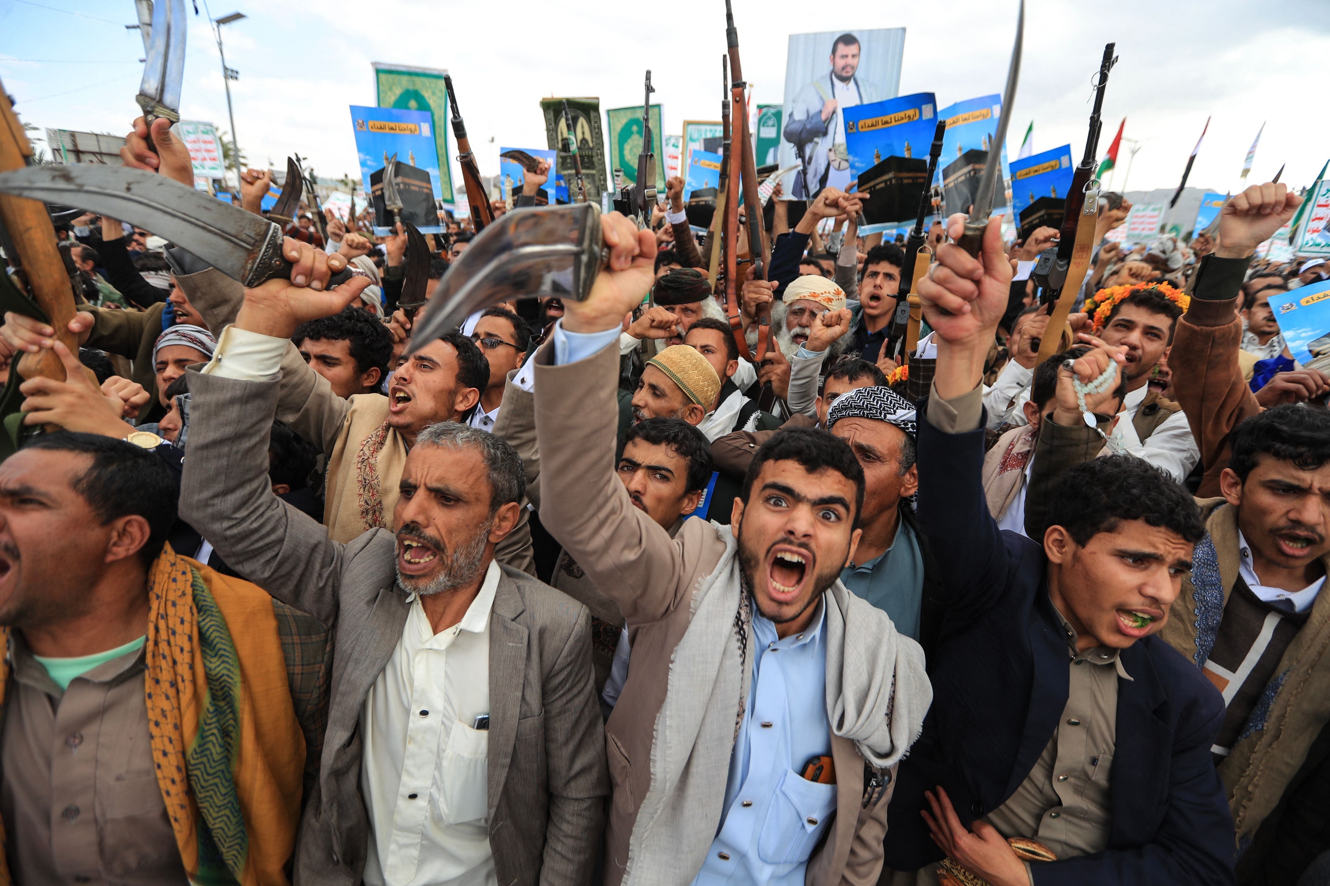 Männer demonstrieren in Sanaa mit erhobenen Waffen und Plakaten mit der Kaaba und arabischer Aufschrift.