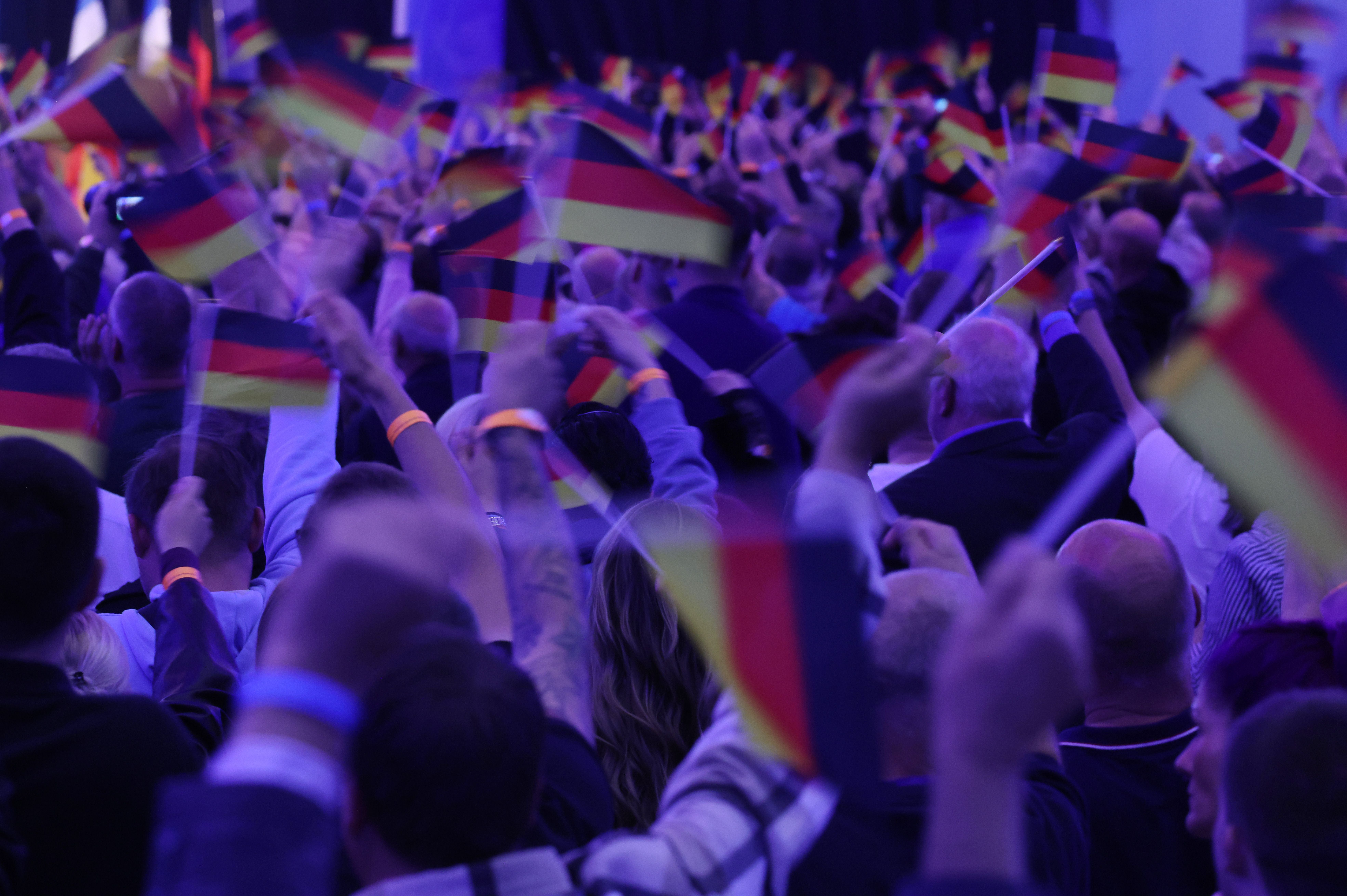 Menschenmenge schwenkt zahlreiche Deutschlandfahnen auf einer politischen Wahlkampfveranstaltung.