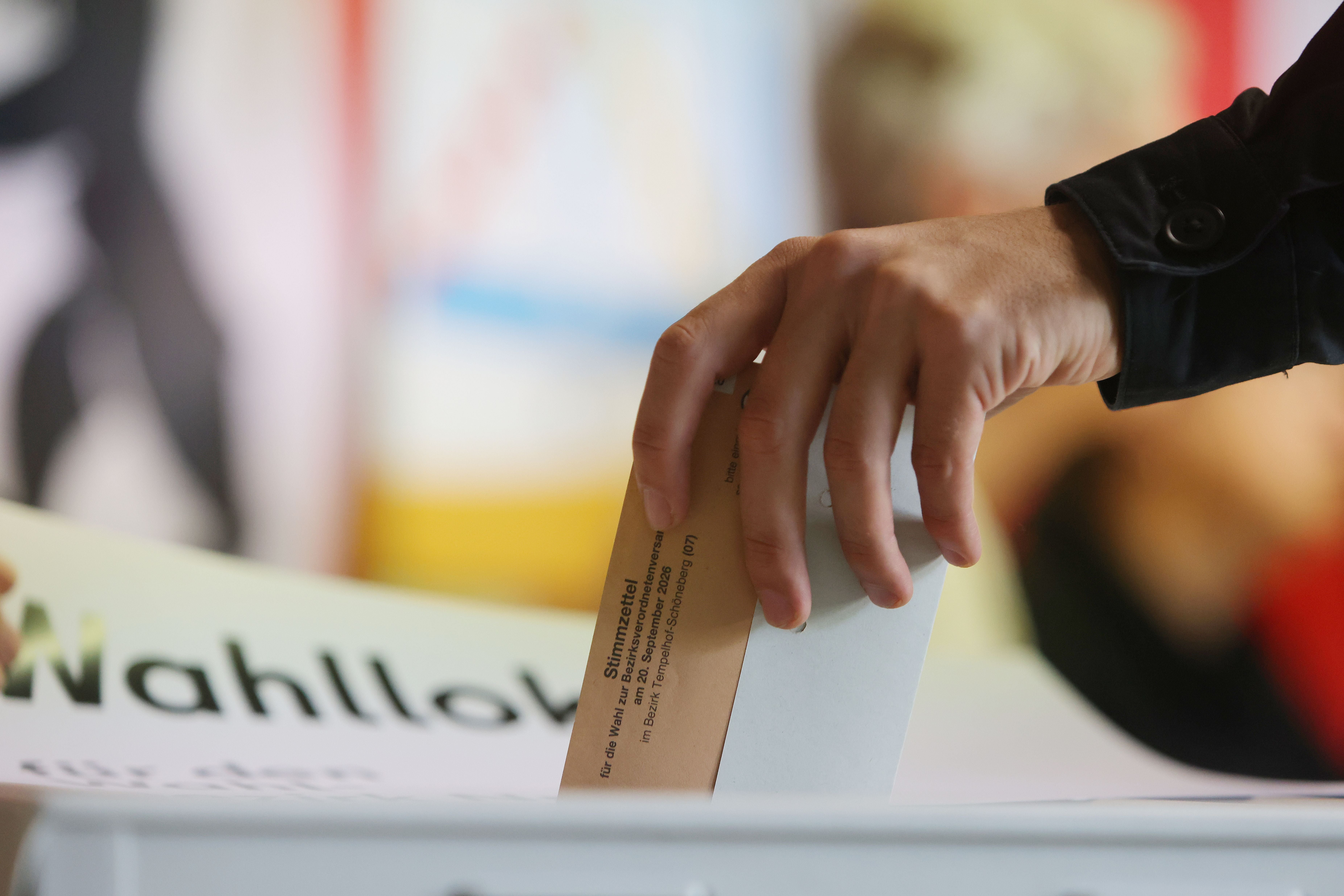 Eine Hand wirft einen Stimmzettel in eine Wahlurne bei einer Wahl in Berlin.