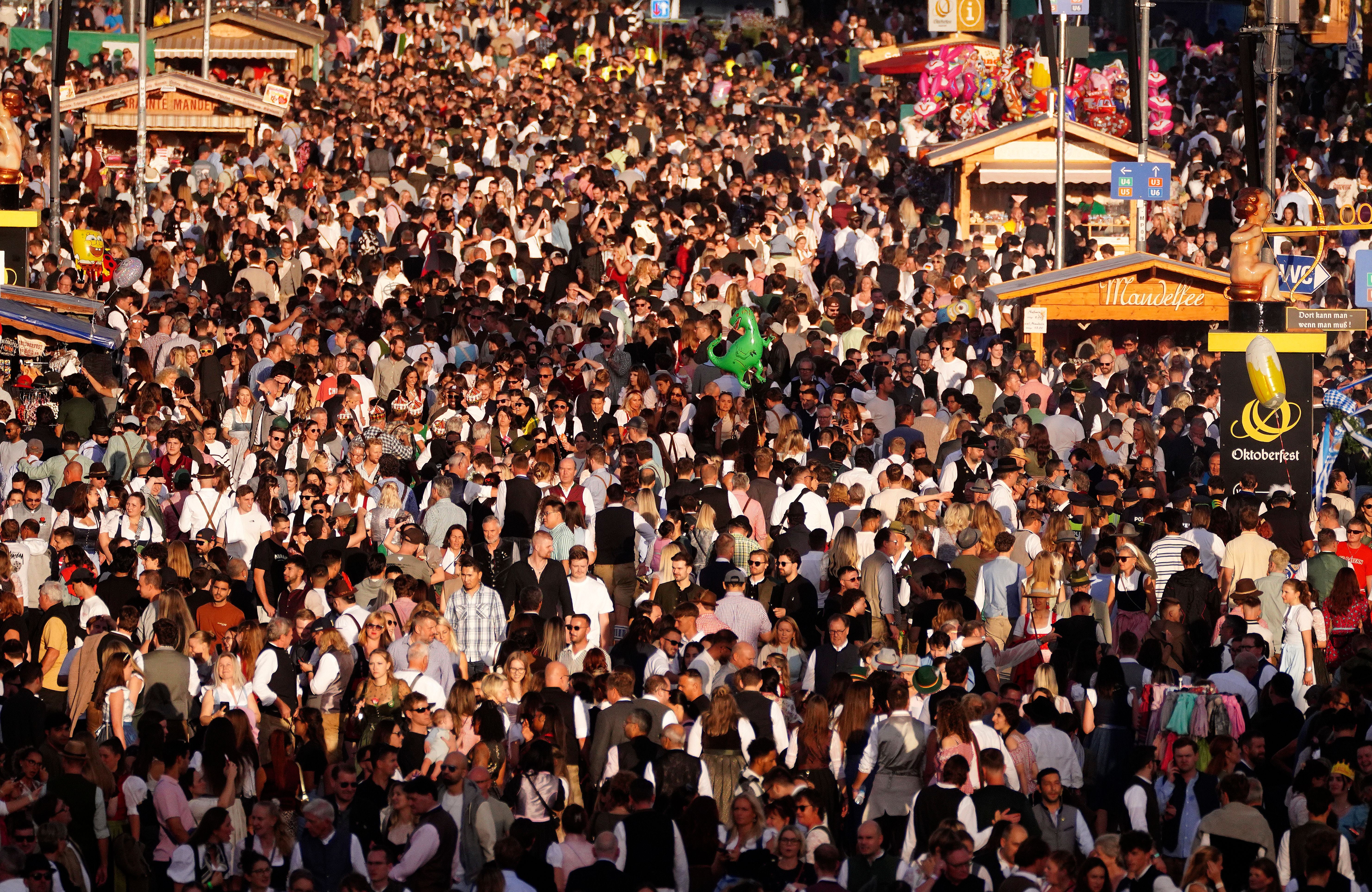 Menschenmenge feiert auf dem Oktoberfest-Gelände in München bei sonnigem Wetter.