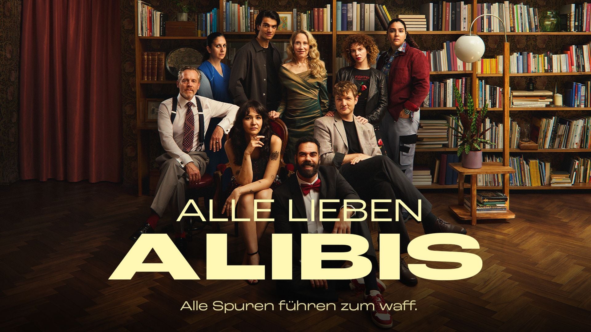 Neun Personen posieren vor Bücherregalen mit dem Text "Alle lieben Alibis".