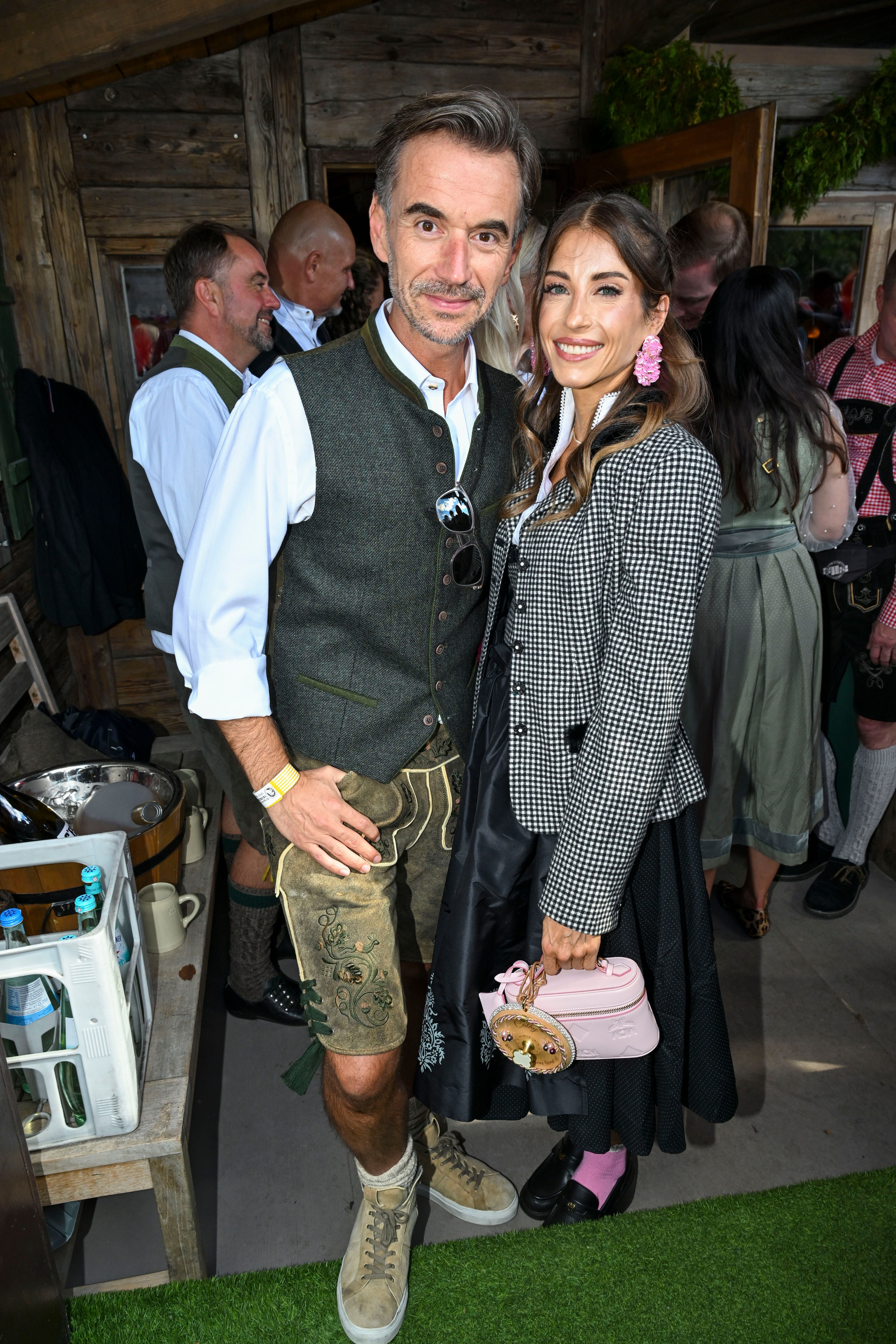 Ein Mann und eine Frau in traditioneller Tracht lächeln bei einer Veranstaltung im Festzelt.