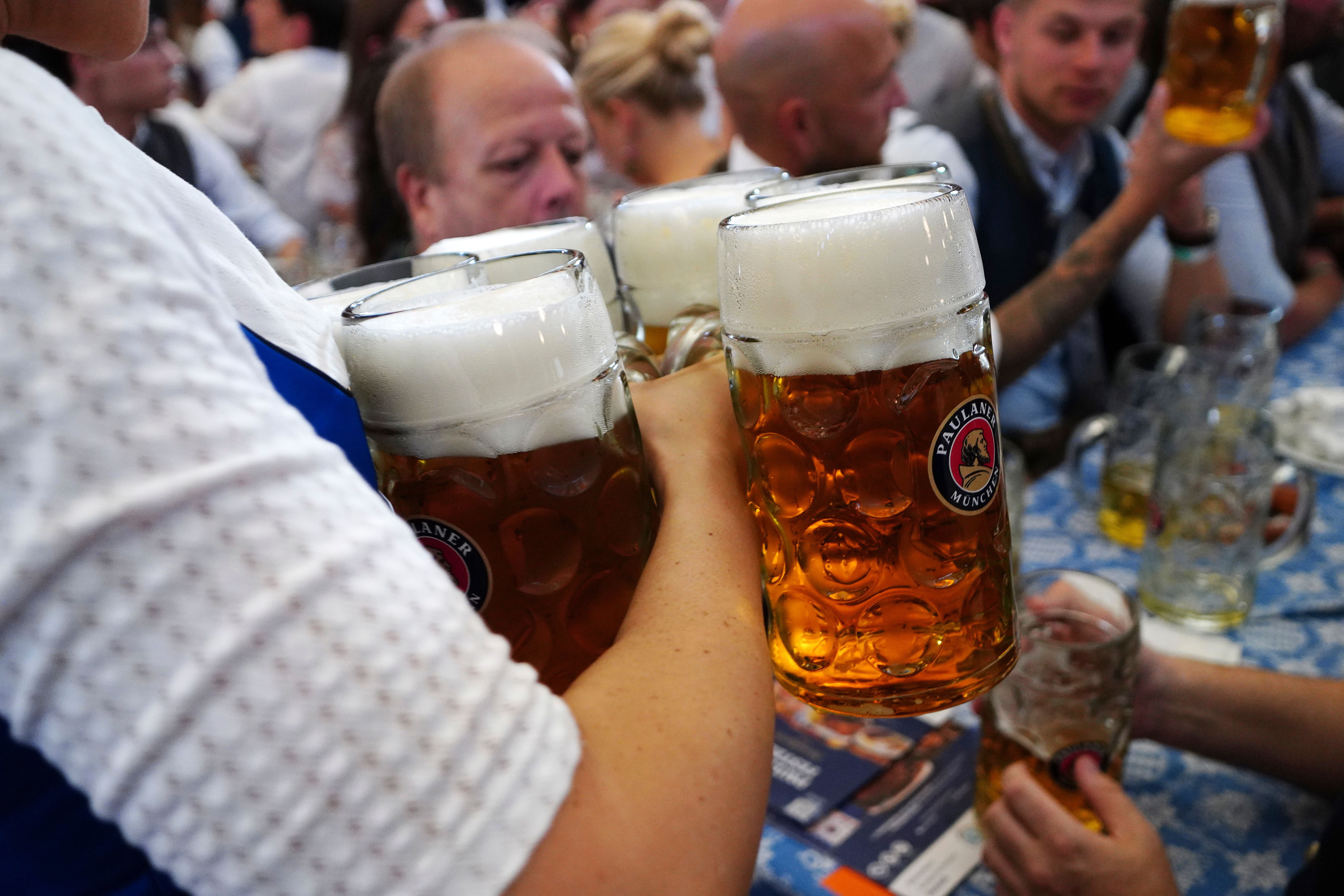 Ein Kellner trägt mehrere große Bierkrüge auf dem Oktoberfest in München.
