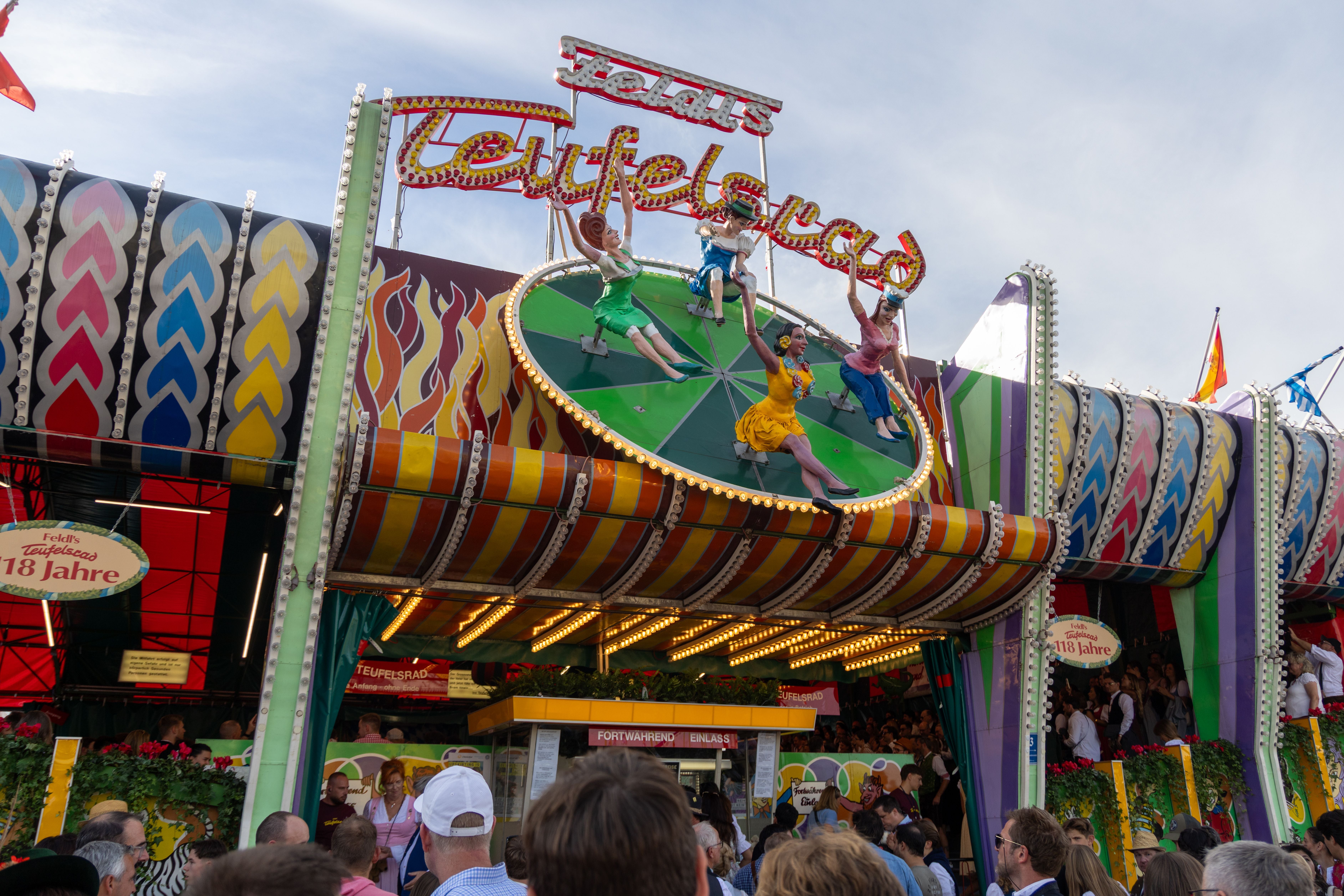 Bunt geschmücktes Teufelsrad-Fahrgeschäft mit vielen Besuchern auf dem Münchner Oktoberfest.