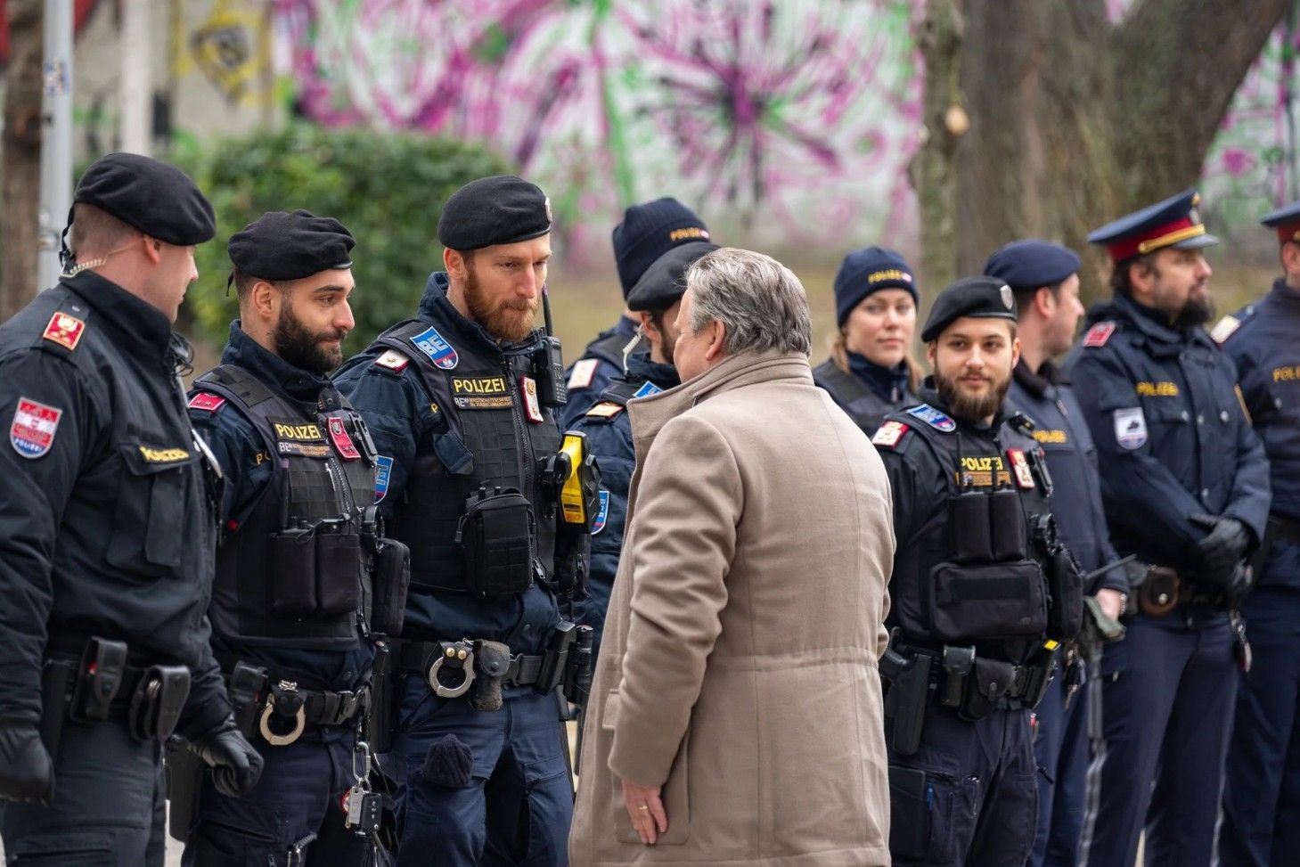 Wiens Bürgermeister Michael Ludwig spricht draußen mit einer Gruppe Polizisten in Uniform.