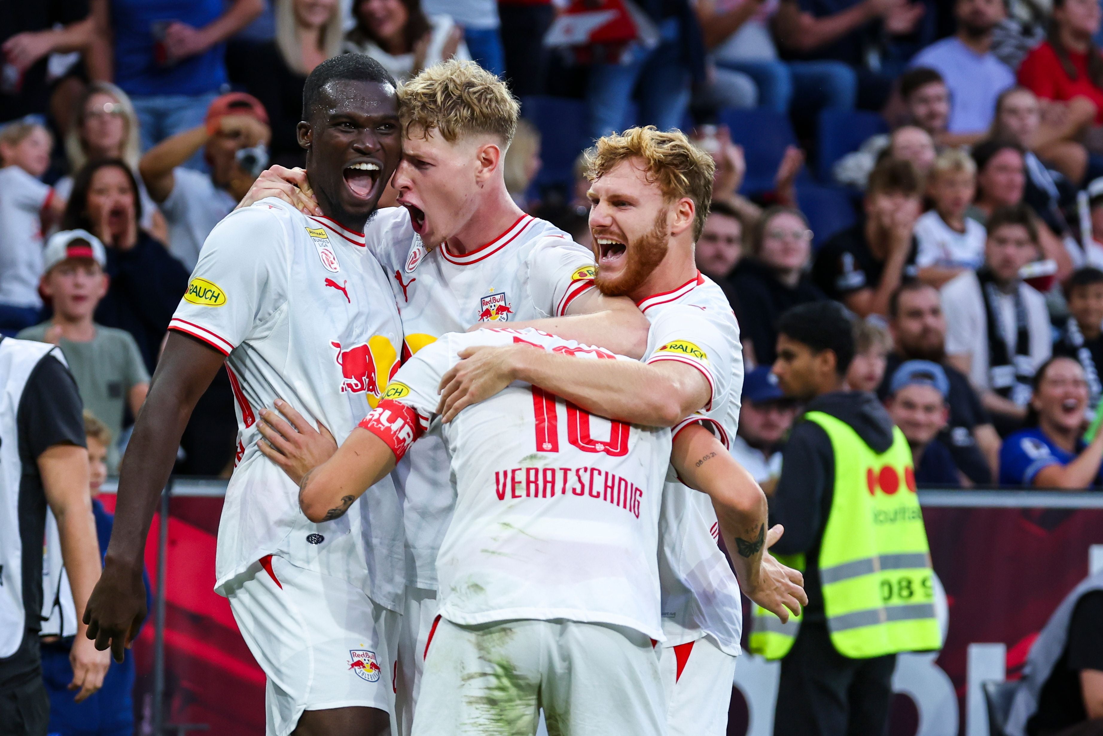 Vier Salzburger Fußballspieler jubeln nach einem Tor und umarmen sich auf dem Spielfeld.
