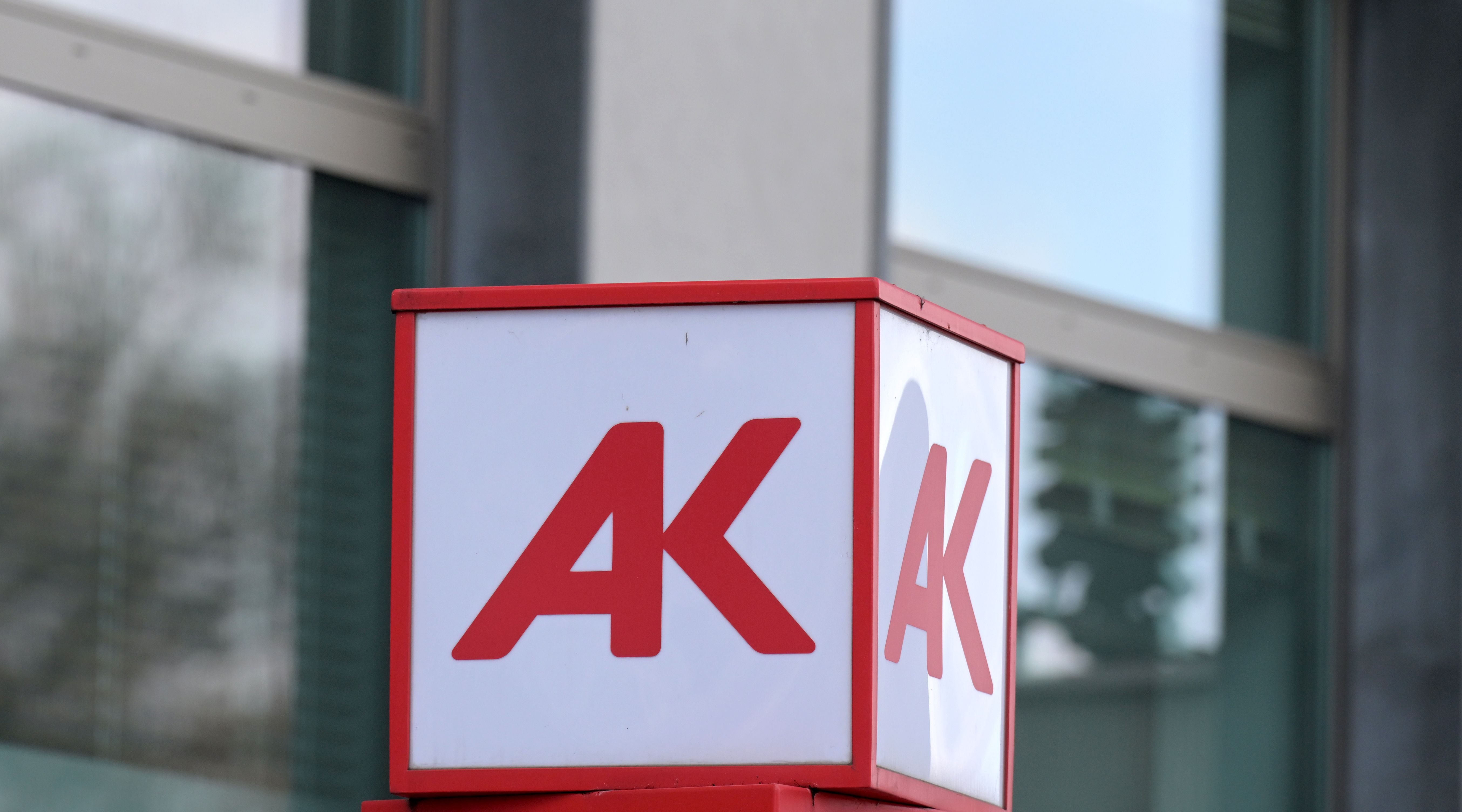 Logo der Arbeiterkammer (AK) auf einem Schild vor einem modernen Gebäude.