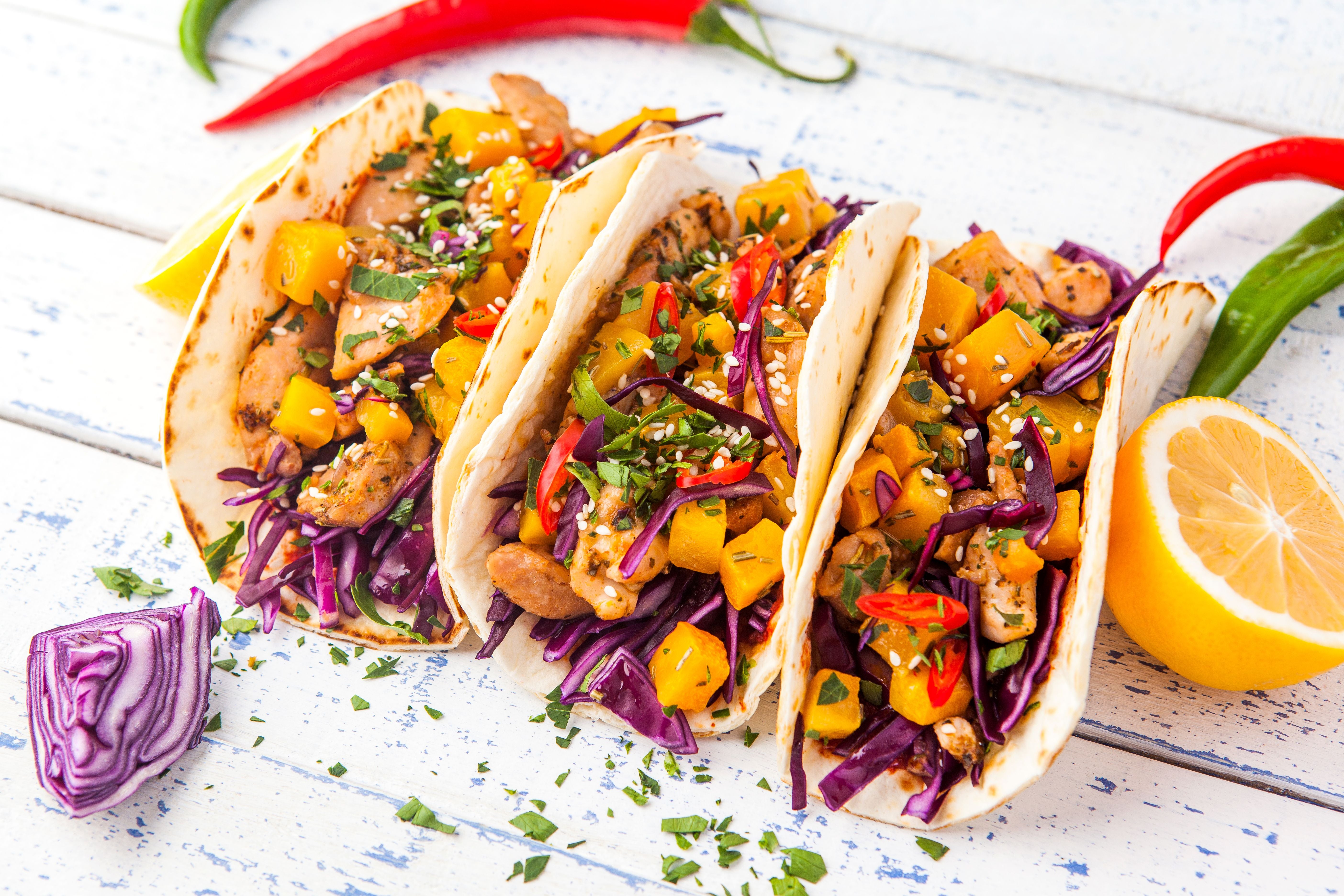 Drei mexikanische Schweinefleisch-Tacos mit Gemüse, Rotkohl und frischen Kräutern.