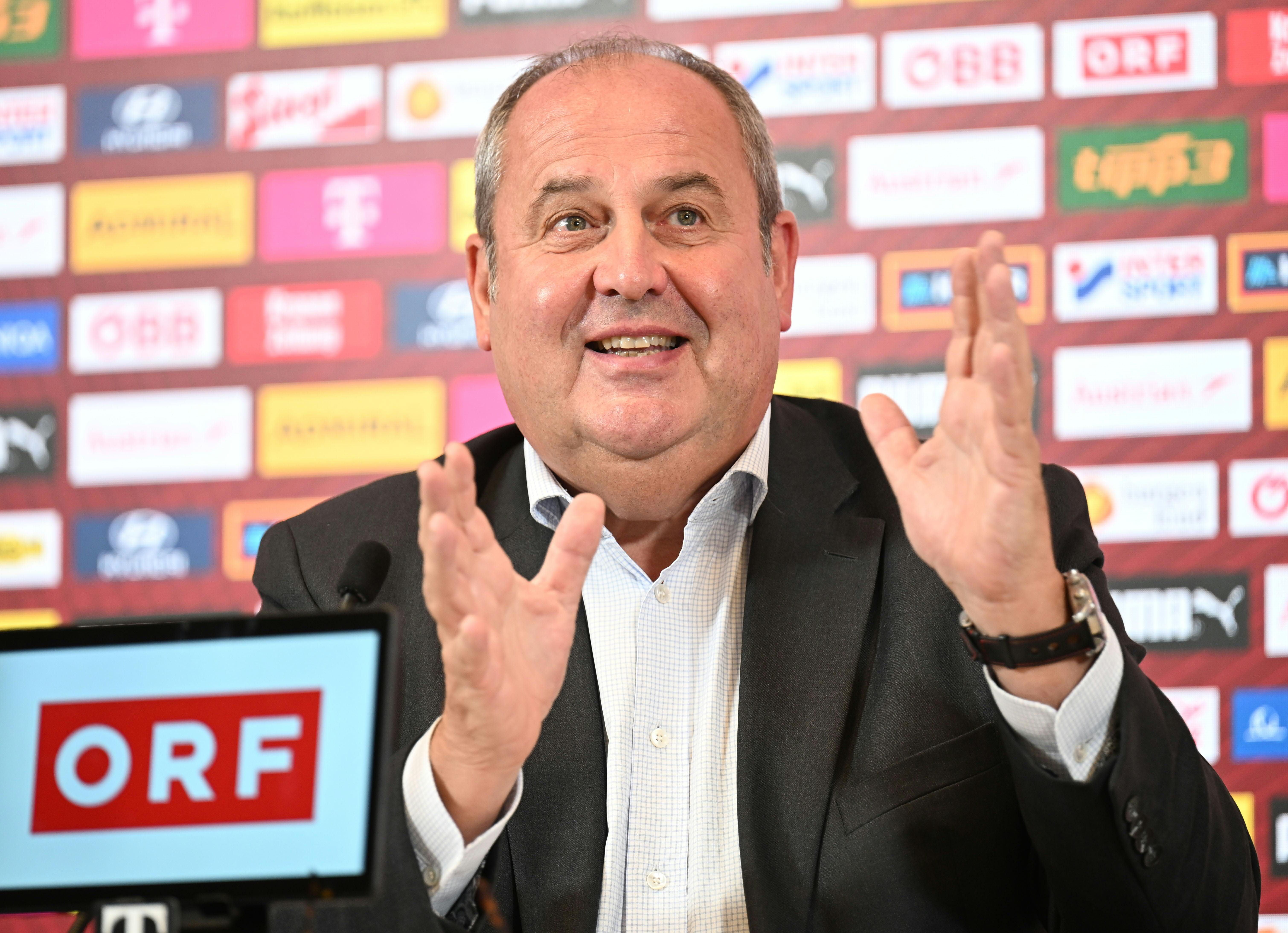 Ein Mann im Anzug spricht gestikulierend bei einer Pressekonferenz, ORF-Logo im Vordergrund.