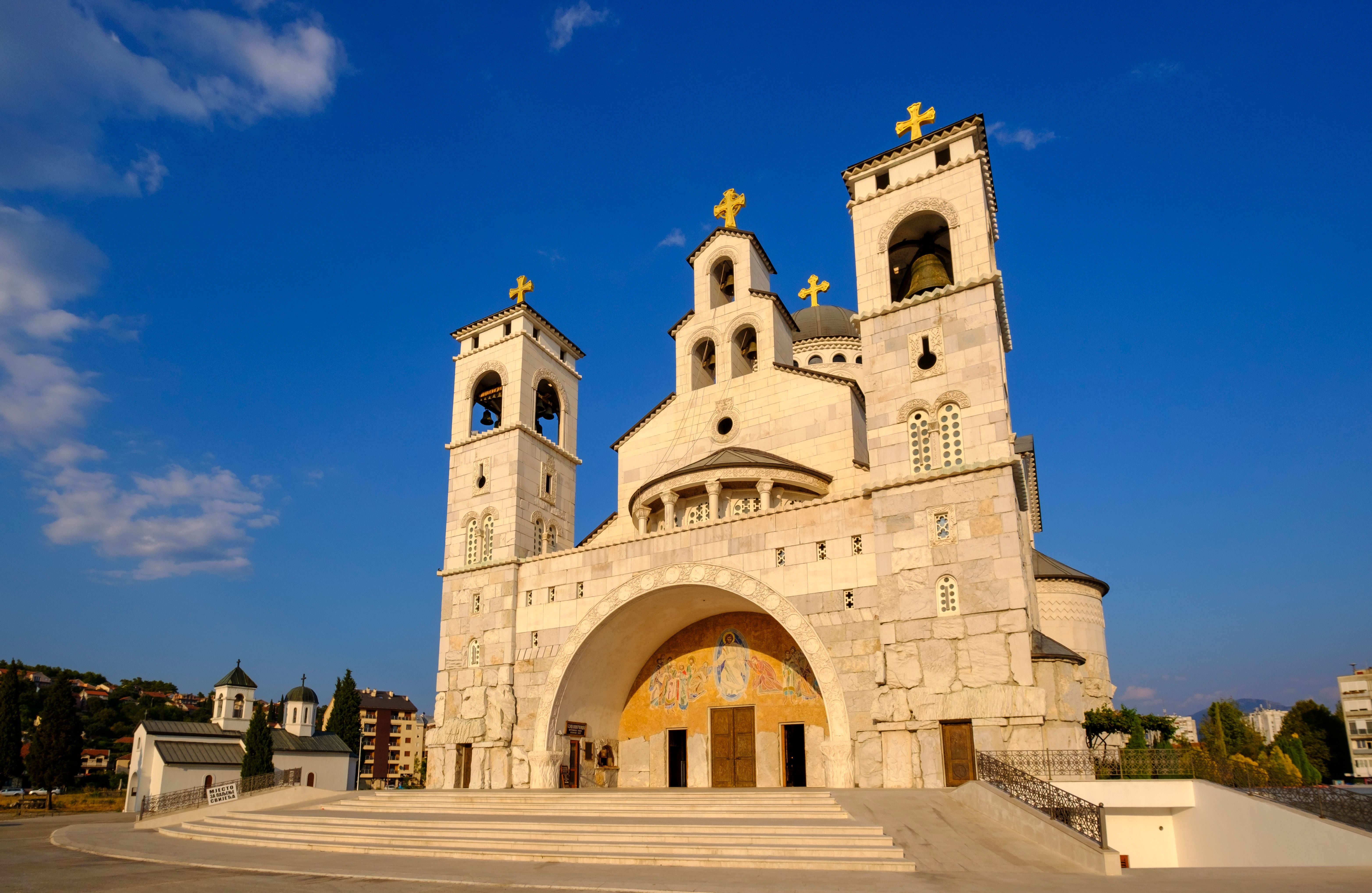 Große orthodoxe Kathedrale mit goldenen Kreuzen in Podgorica, Montenegro bei blauem Himmel.
