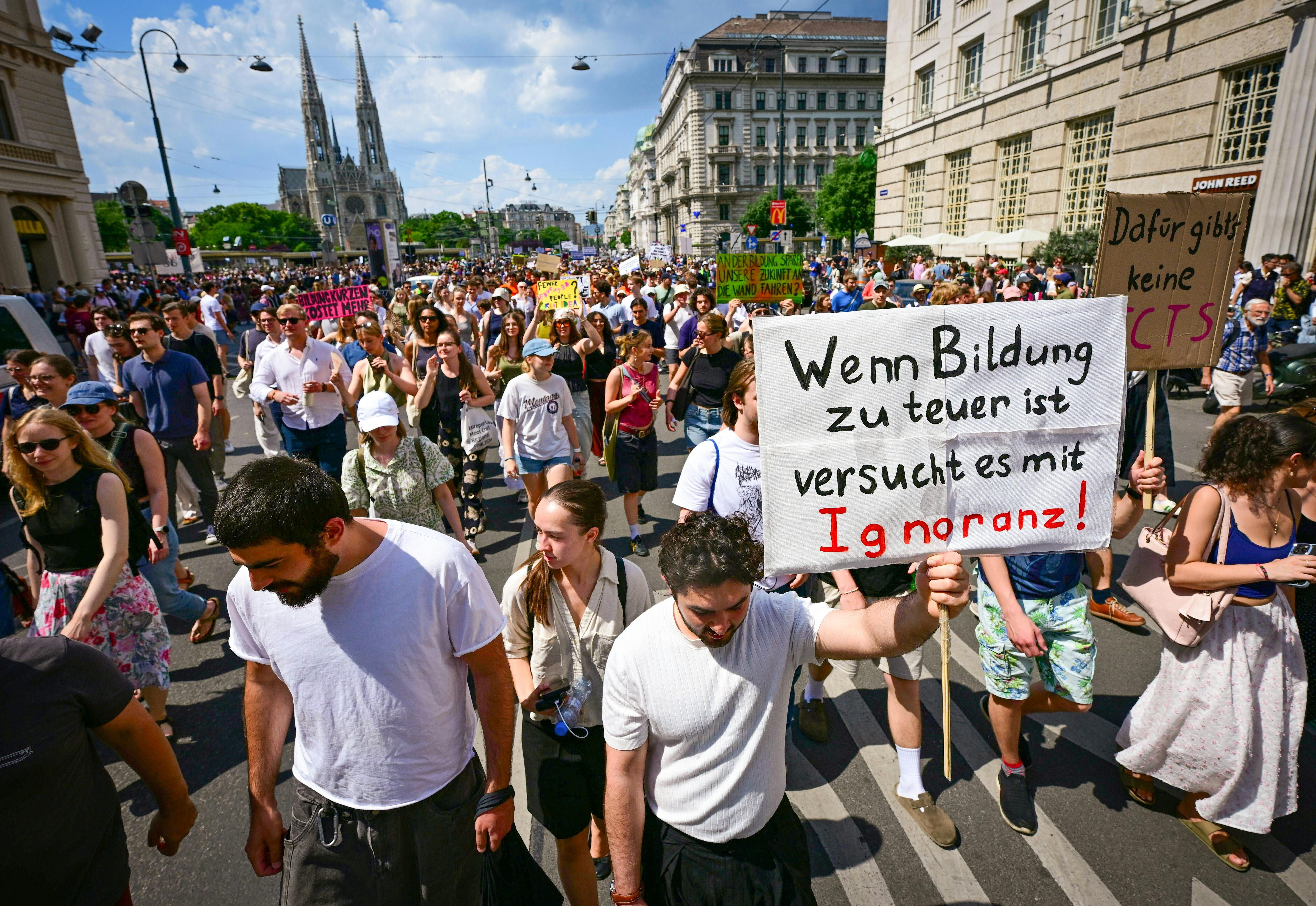 Große Demonstration in Wien mit Plakaten gegen Einsparungen an Universitäten bei sonnigem Wetter.