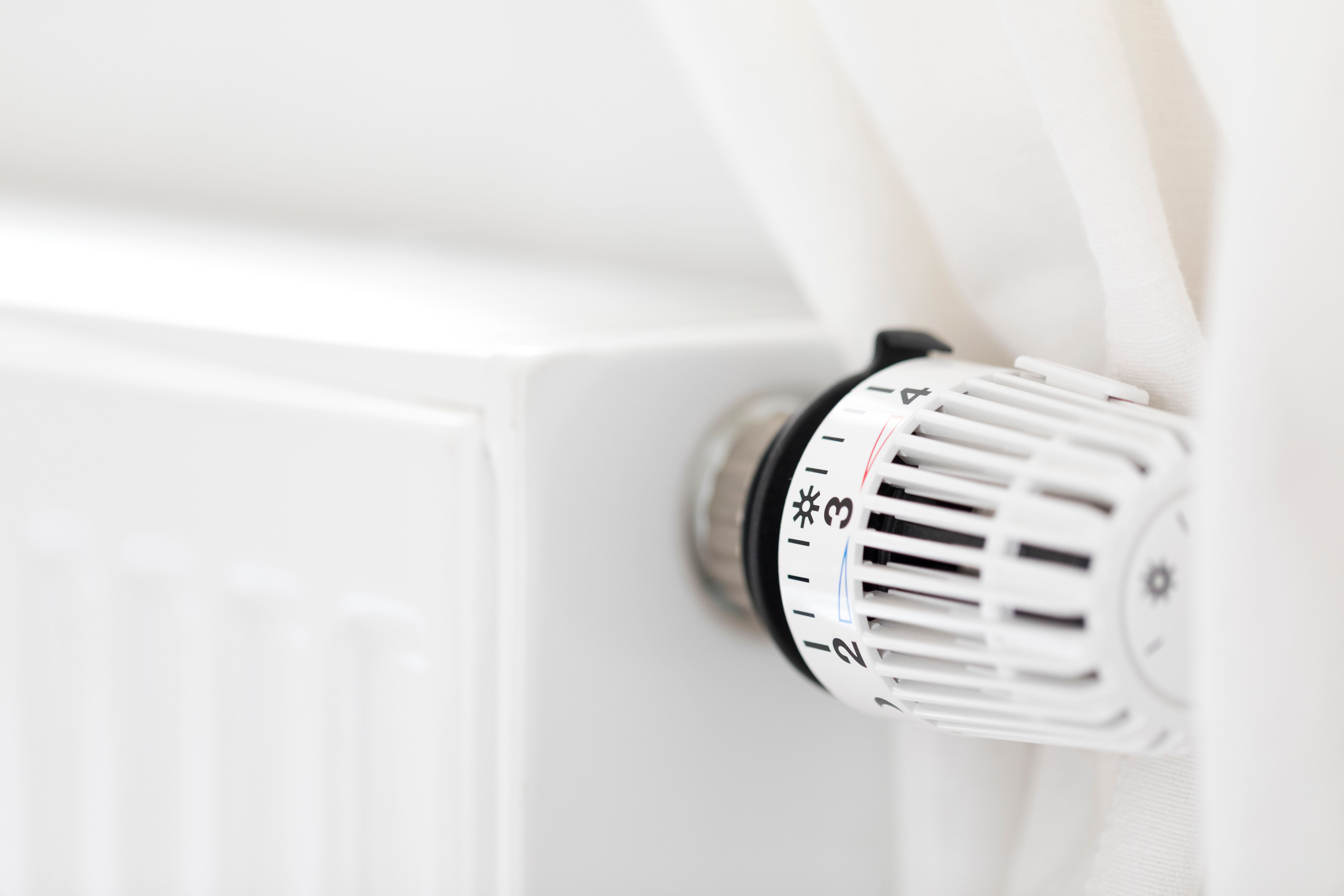 Nahaufnahme eines weißen Heizkörper-Thermostats mit sichtbaren Temperatureinstellungen.