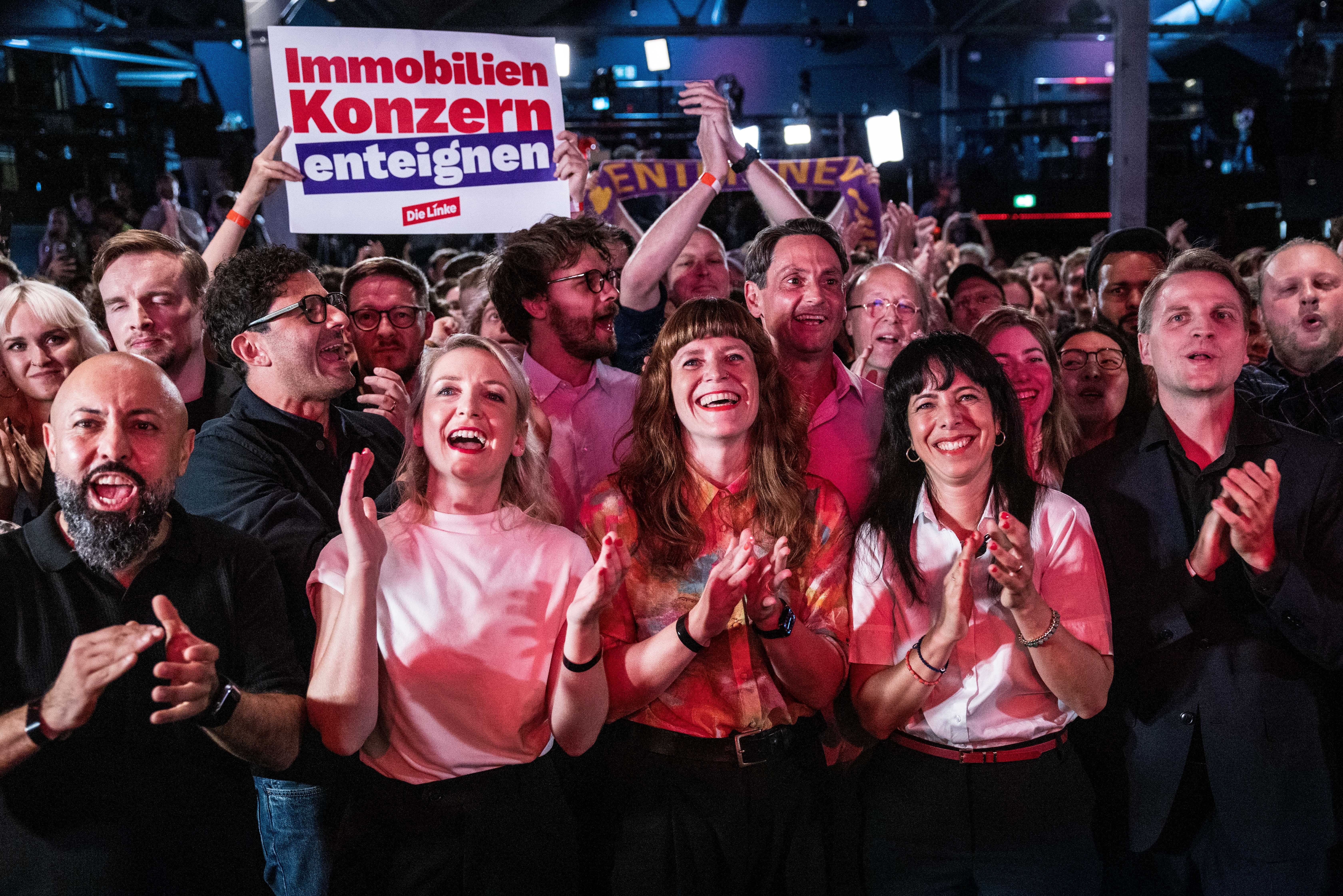 Menschenmenge jubelt und applaudiert, ein Schild mit „Immobilien Konzern enteignen“ wird hochgehalten.