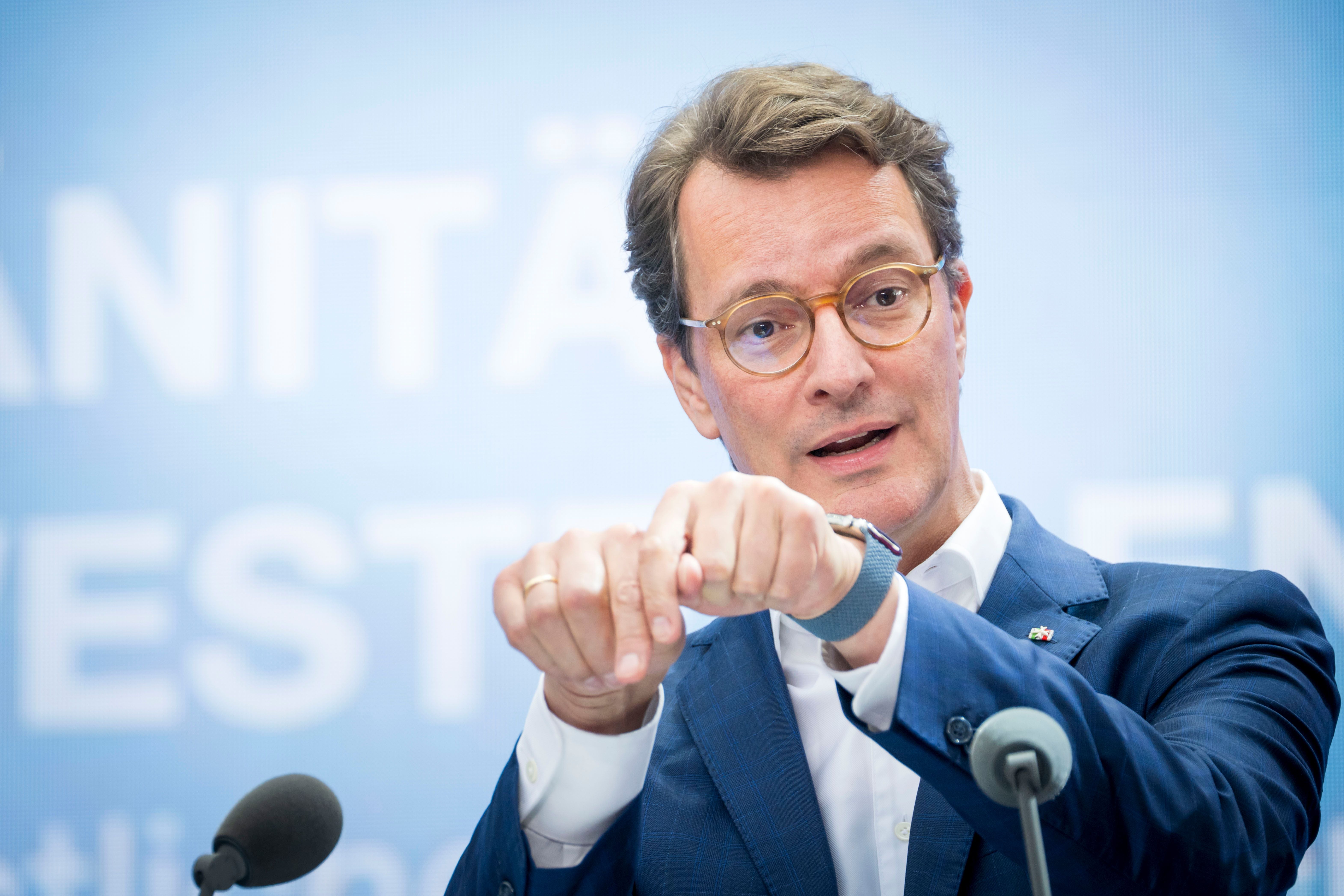 Ein Mann im Anzug spricht bei einer Konferenz in ein Mikrofon und gestikuliert mit den Händen.