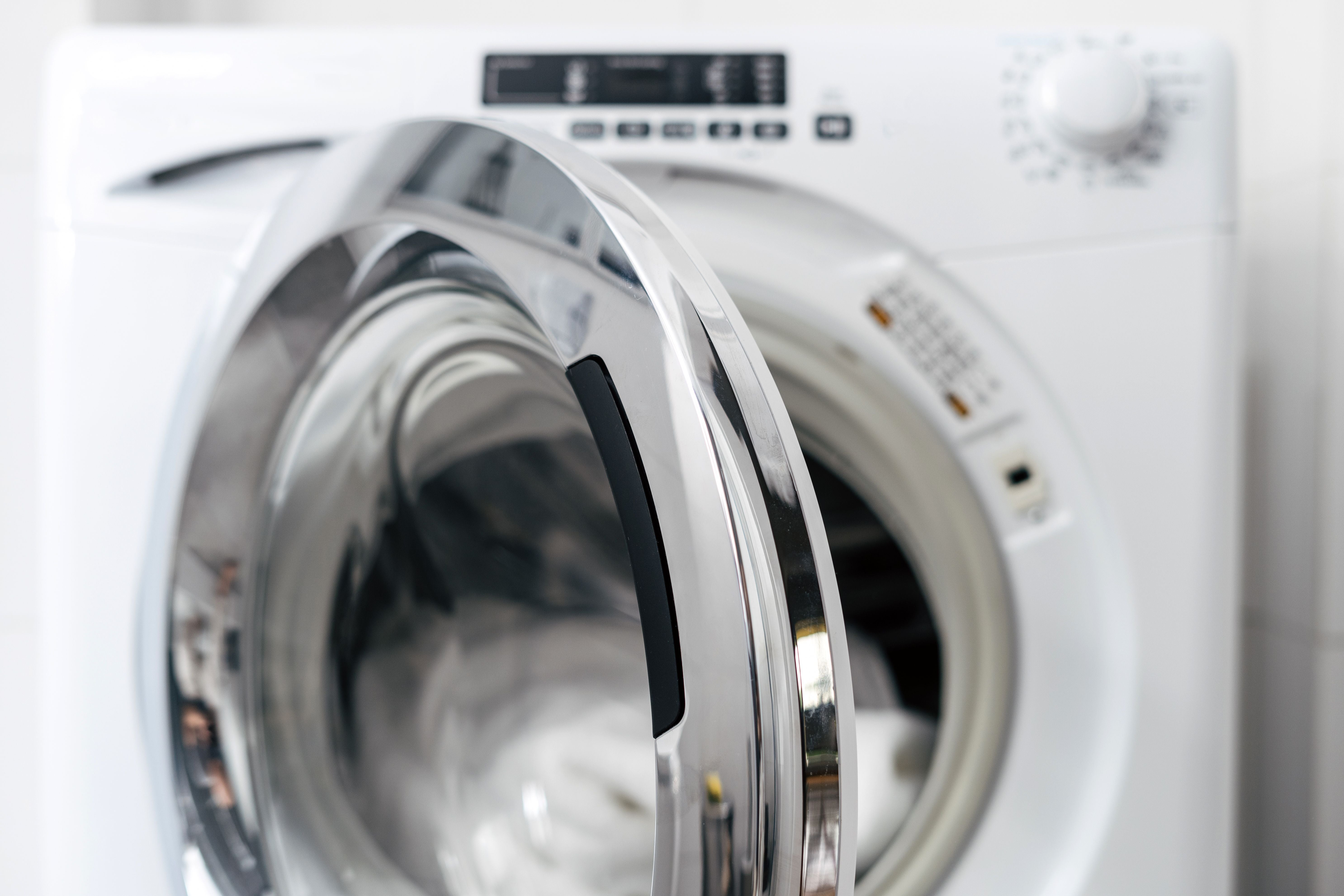 Weiße Waschmaschine mit geöffneter Tür und sauberer Wäsche im Inneren.