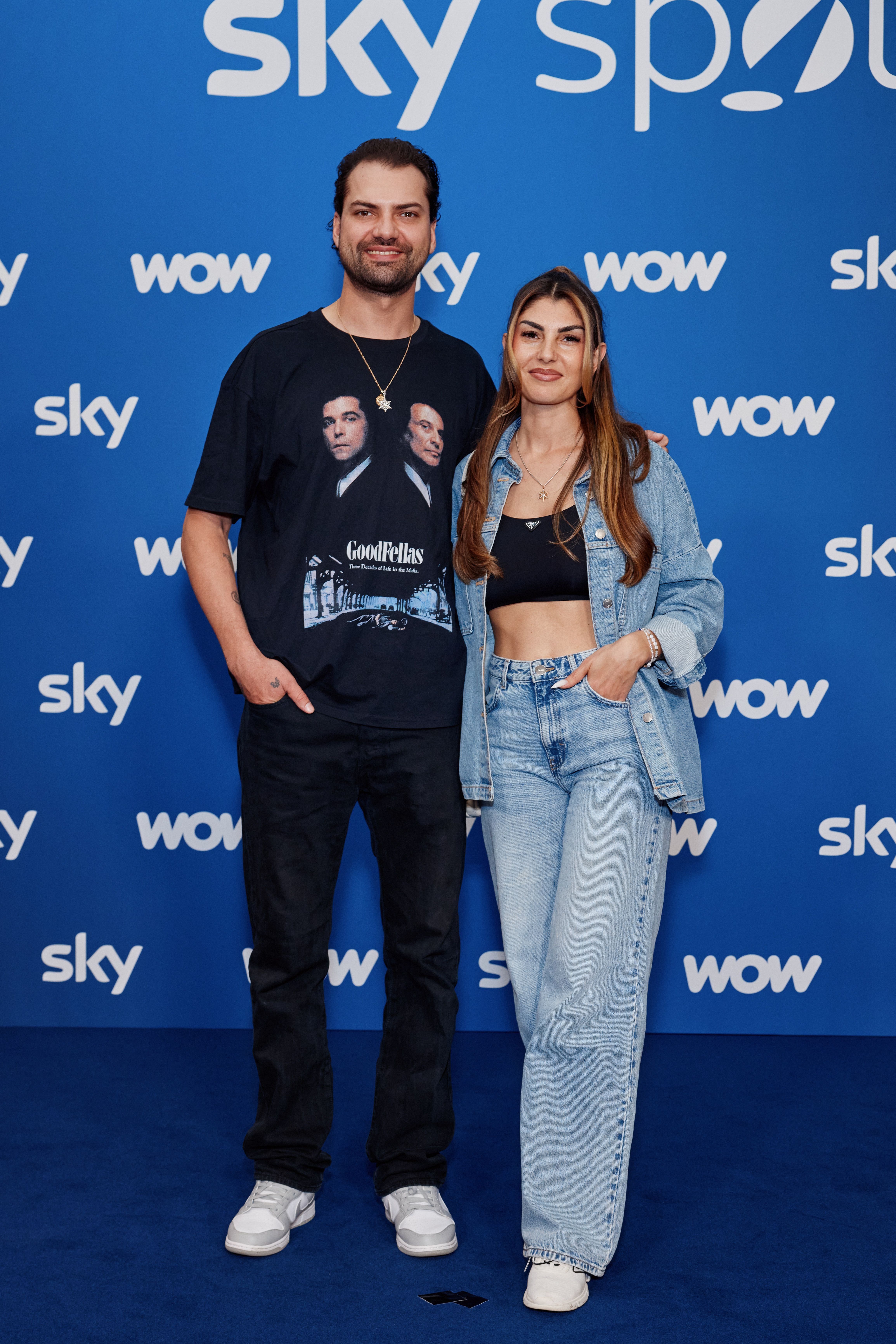 Ein Mann und eine Frau posieren lächelnd vor einer blauen Sky- und WOW-Fotowand.