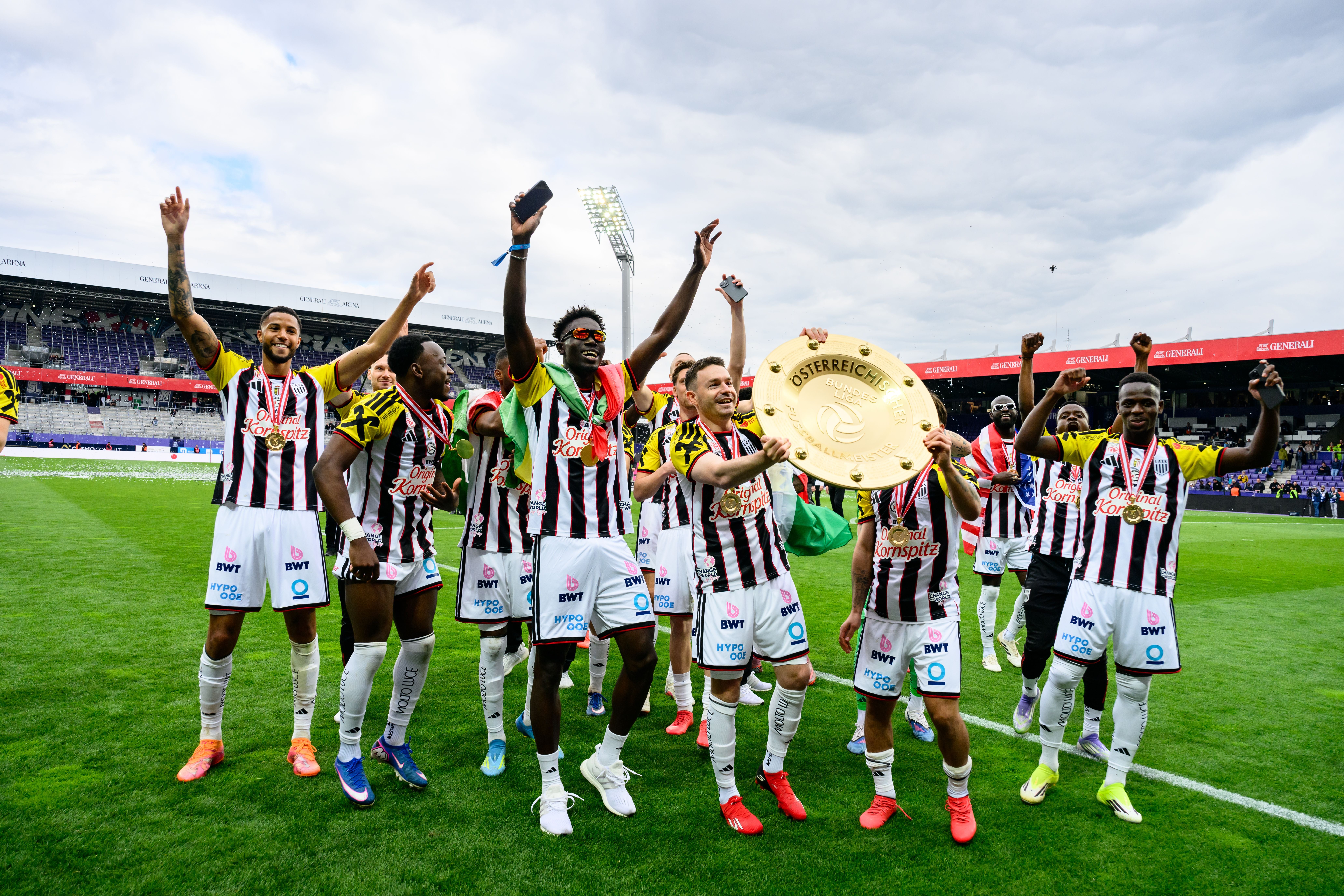 LASK-Spieler feiern mit Meisterteller auf dem Fußballfeld nach dem Titelgewinn in Wien.