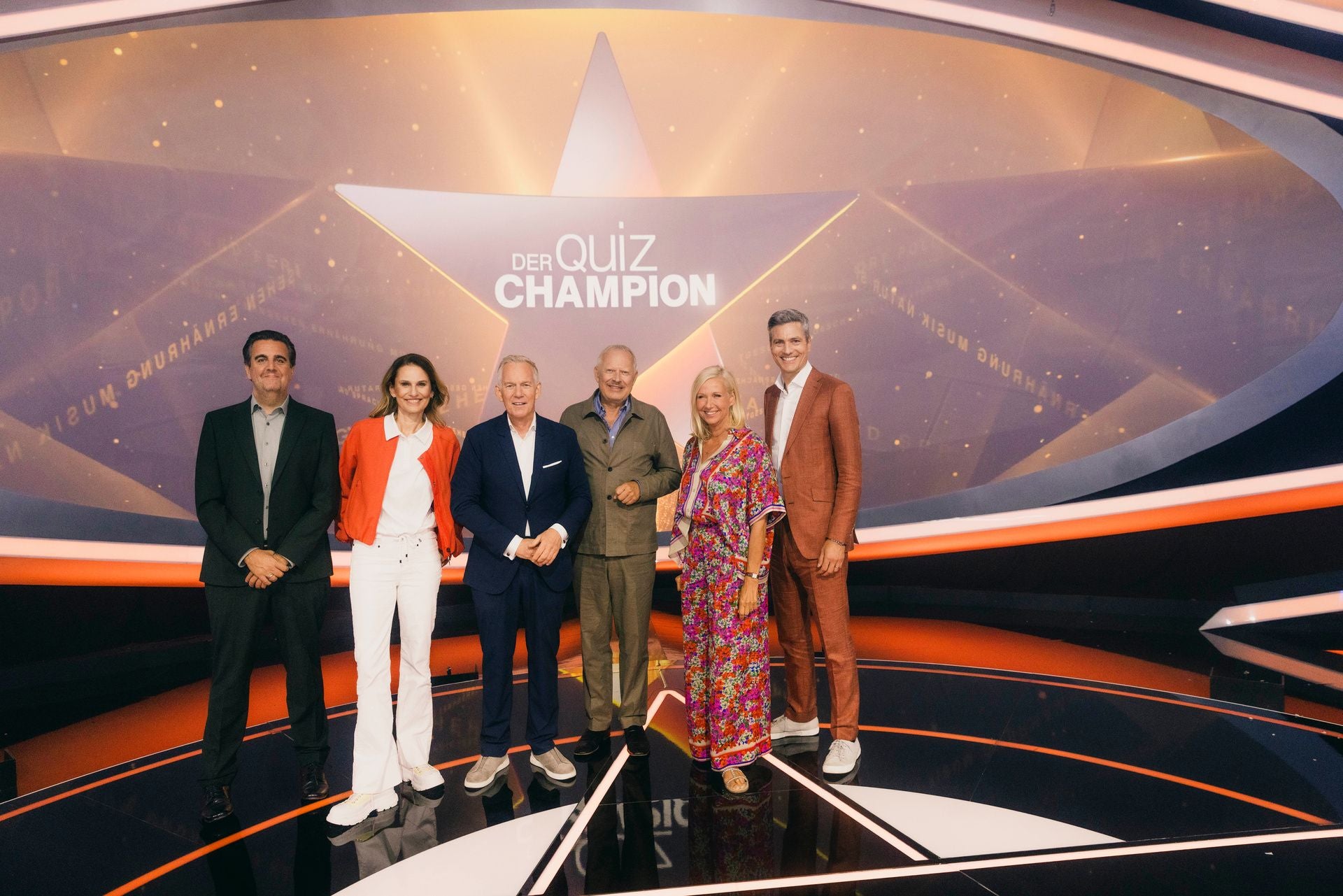 Sechs Personen stehen auf der Bühne der TV-Show "Der Quiz Champion" vor einem großen Stern.