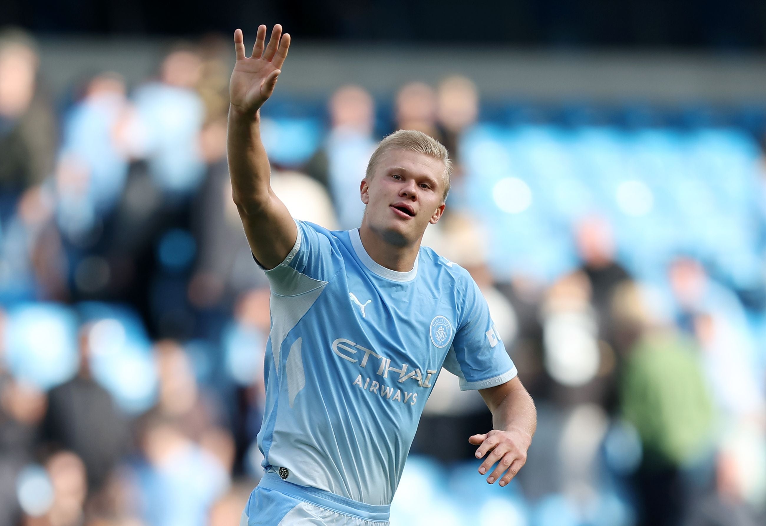 Ein Fußballspieler von Manchester City winkt den Fans im Stadion zu.