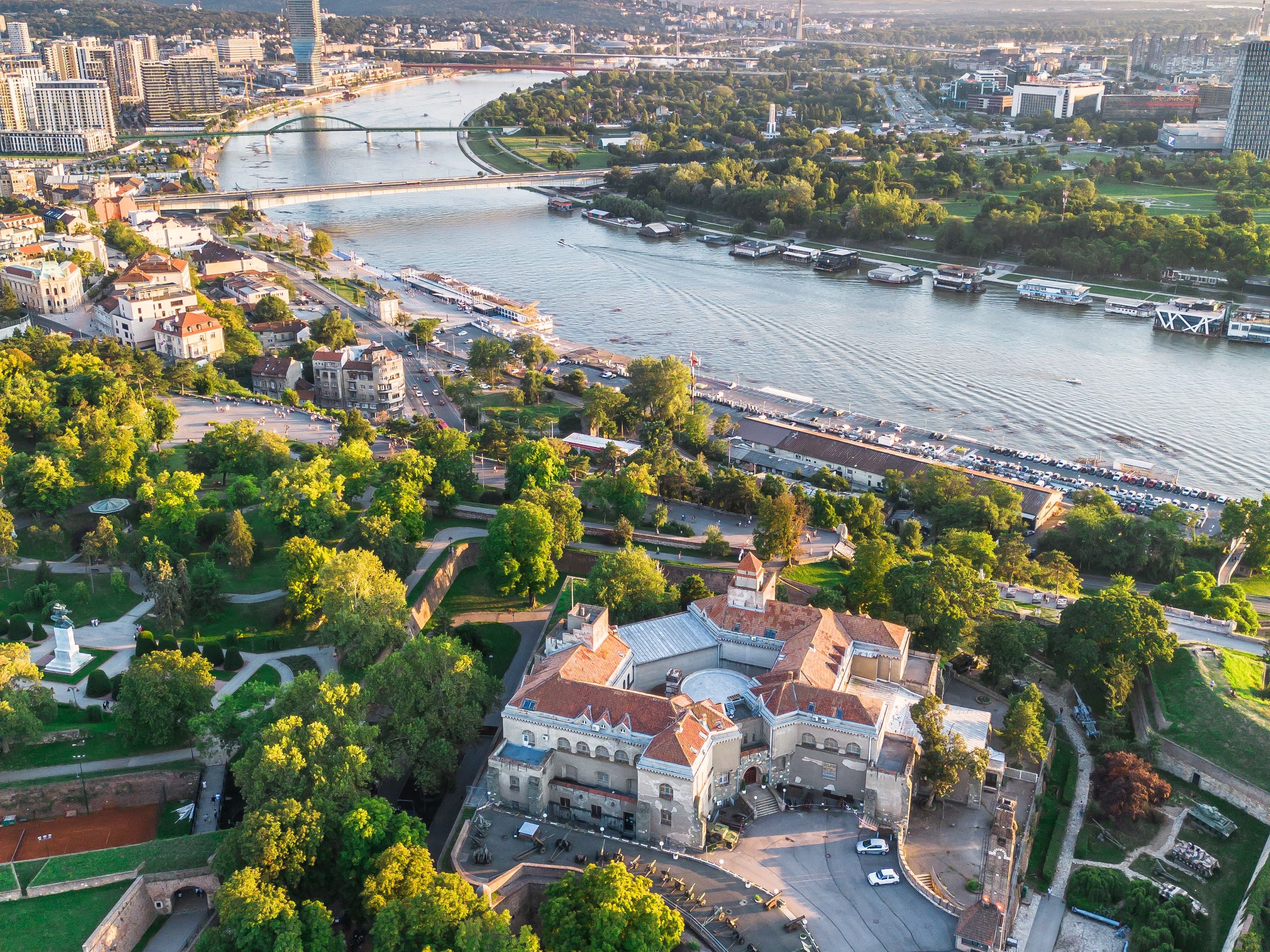 Luftaufnahme von Belgrad mit Fluss, Sava- und Donau-Brücken sowie grünen Parks und Gebäuden.