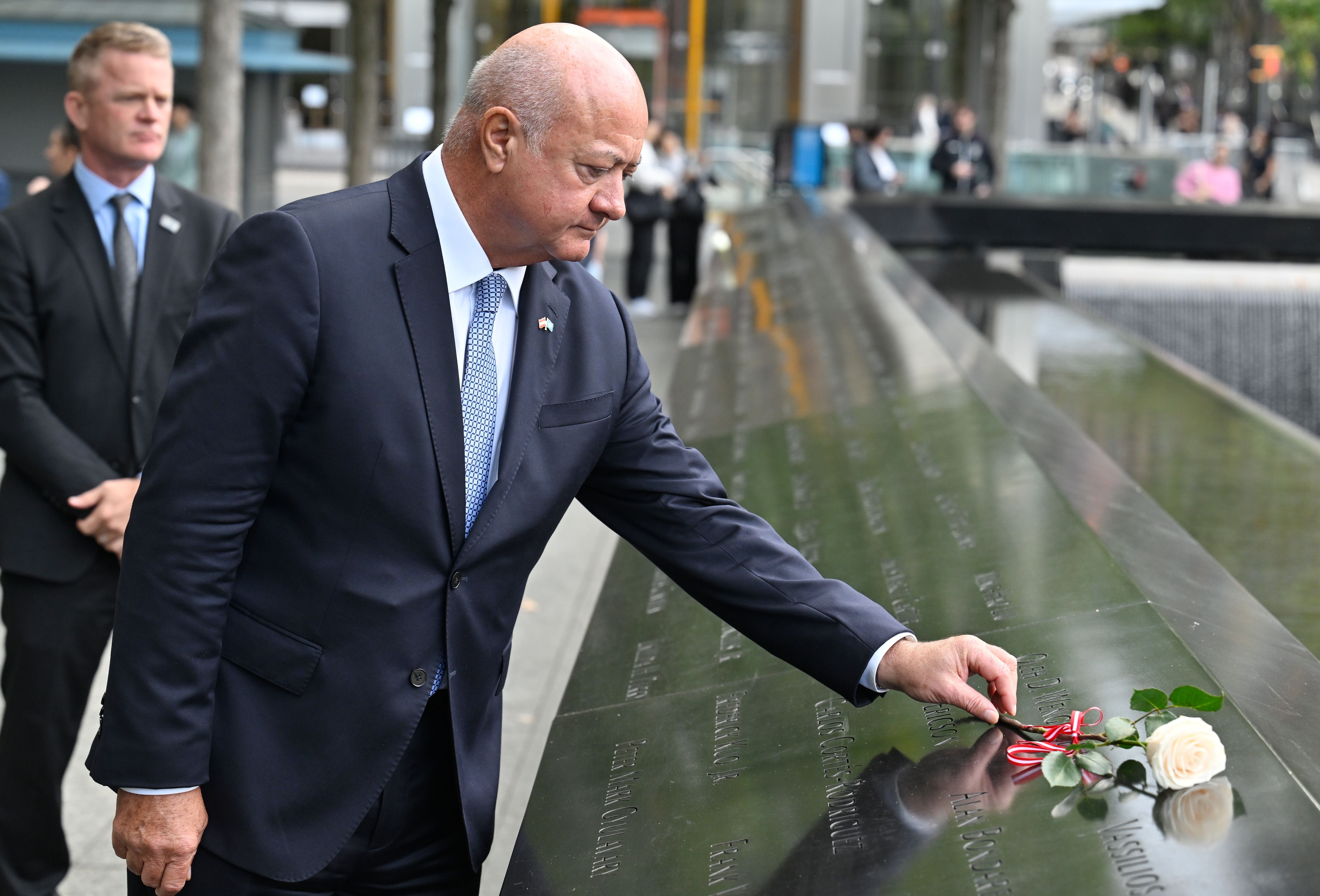 Ein Mann im Anzug legt eine weiße Rose an der 9/11-Gedenkstätte in New York nieder.