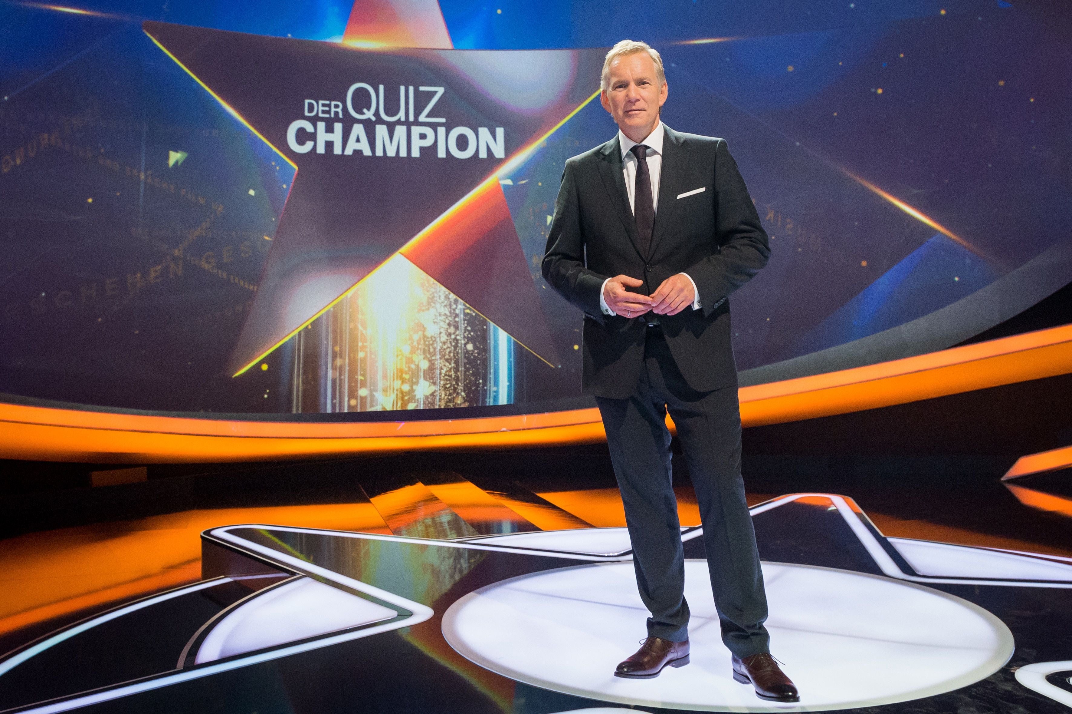 Ein Mann im Anzug steht auf der Bühne der TV-Show "Der Quiz Champion".