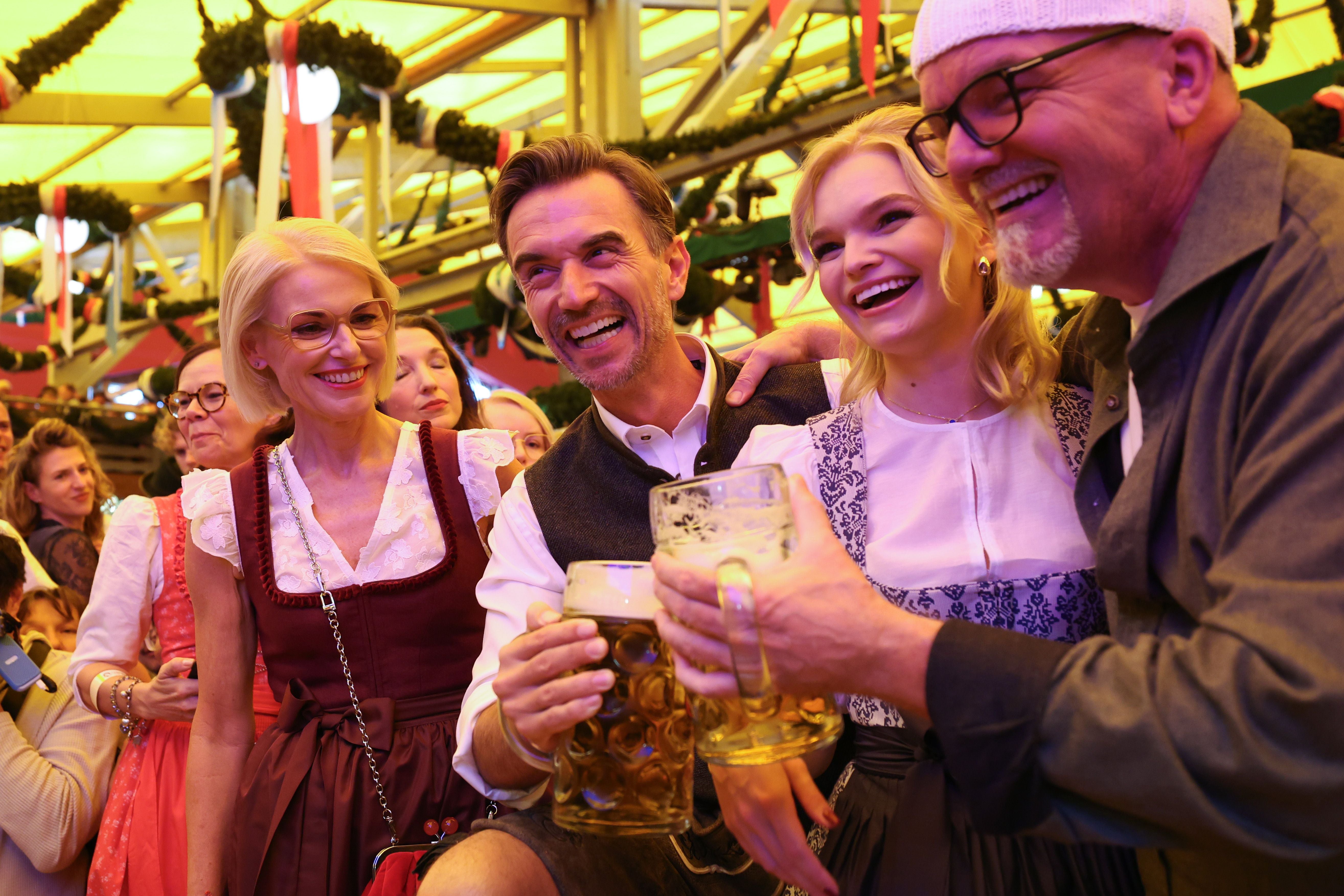 Vier fröhliche Menschen stoßen mit Bierkrügen auf dem Oktoberfest in München an.