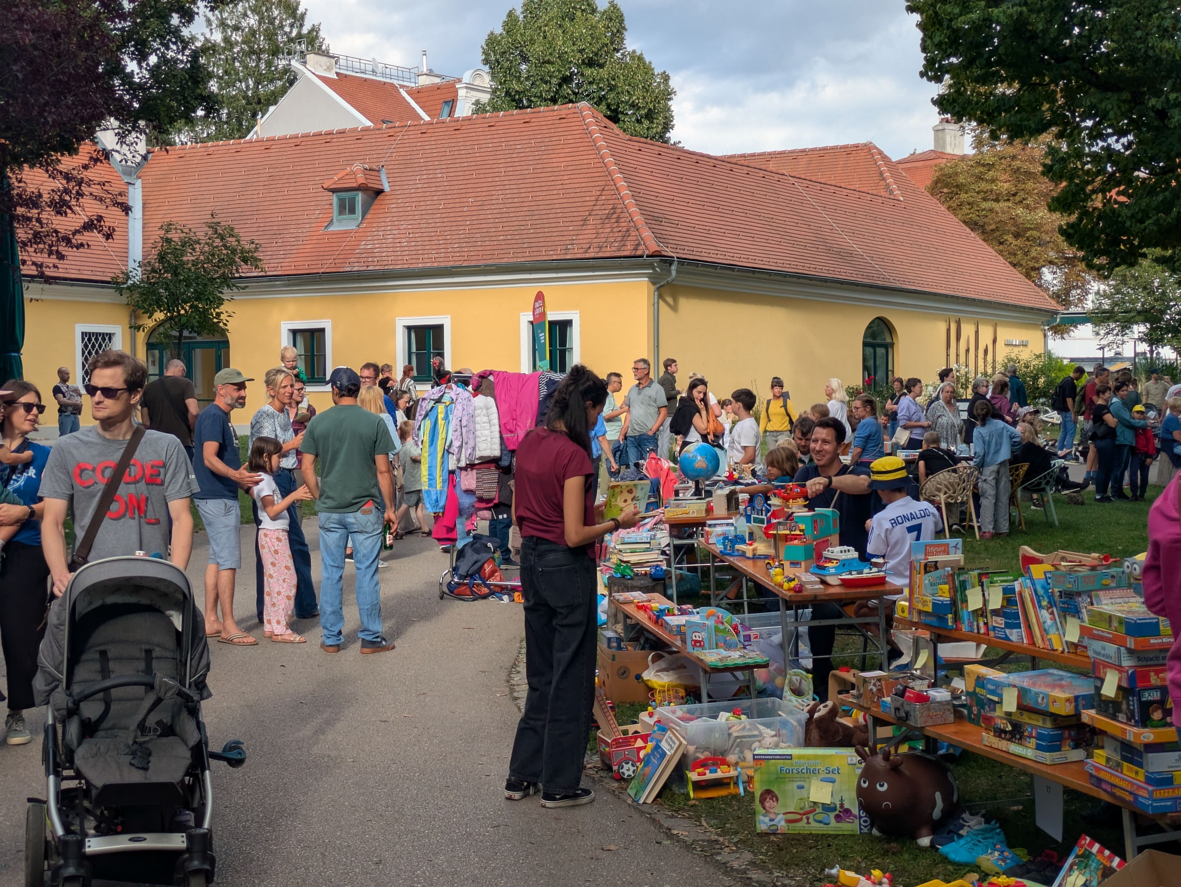 Viele Menschen besuchen ein Charity-Fest mit Flohmarktständen und Spielzeug im Freien.