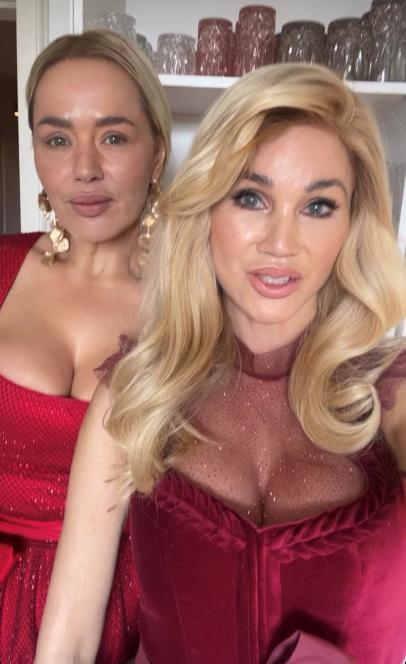 Zwei Frauen in eleganten, roten Kleidern posieren gemeinsam für ein Selfie.