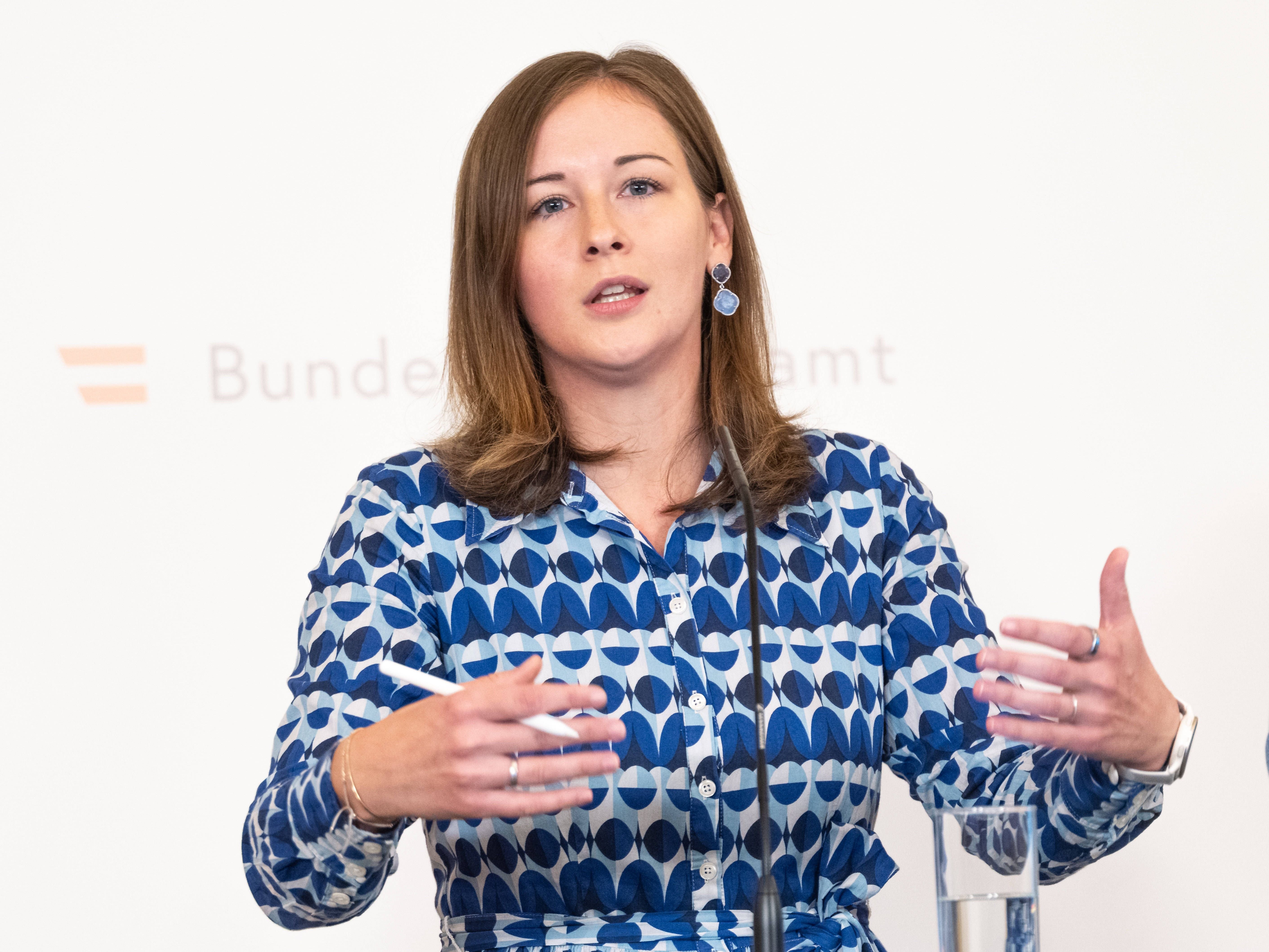 Frau spricht bei einer Pressekonferenz am Rednerpult, neben ihr ein Glas Wasser.