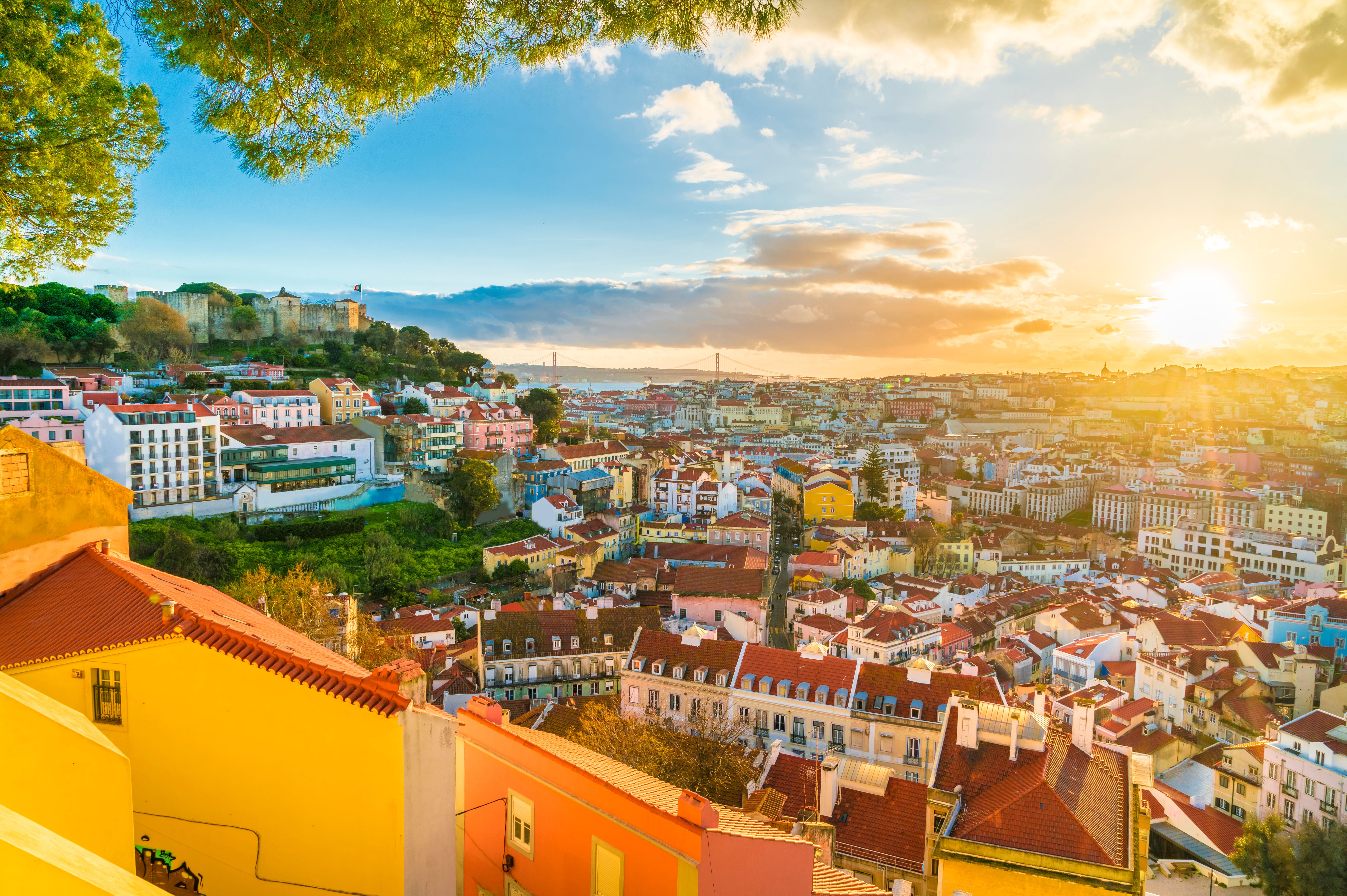 Panorama von Lissabon bei Sonnenuntergang mit bunten Häusern und Hügeln im Hintergrund.