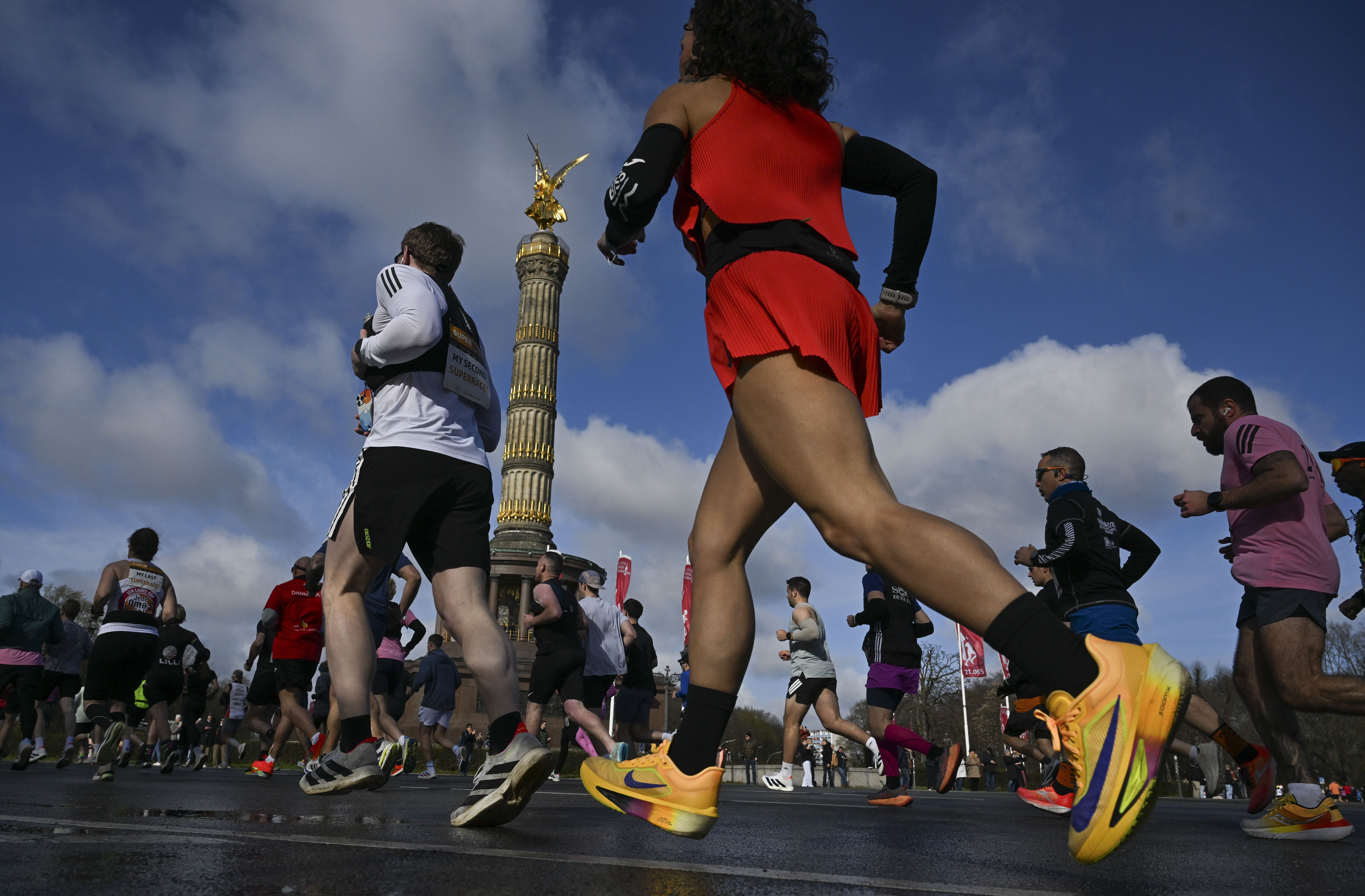 Läuferinnen und Läufer beim Berliner Halbmarathon laufen an der Siegessäule entlang.