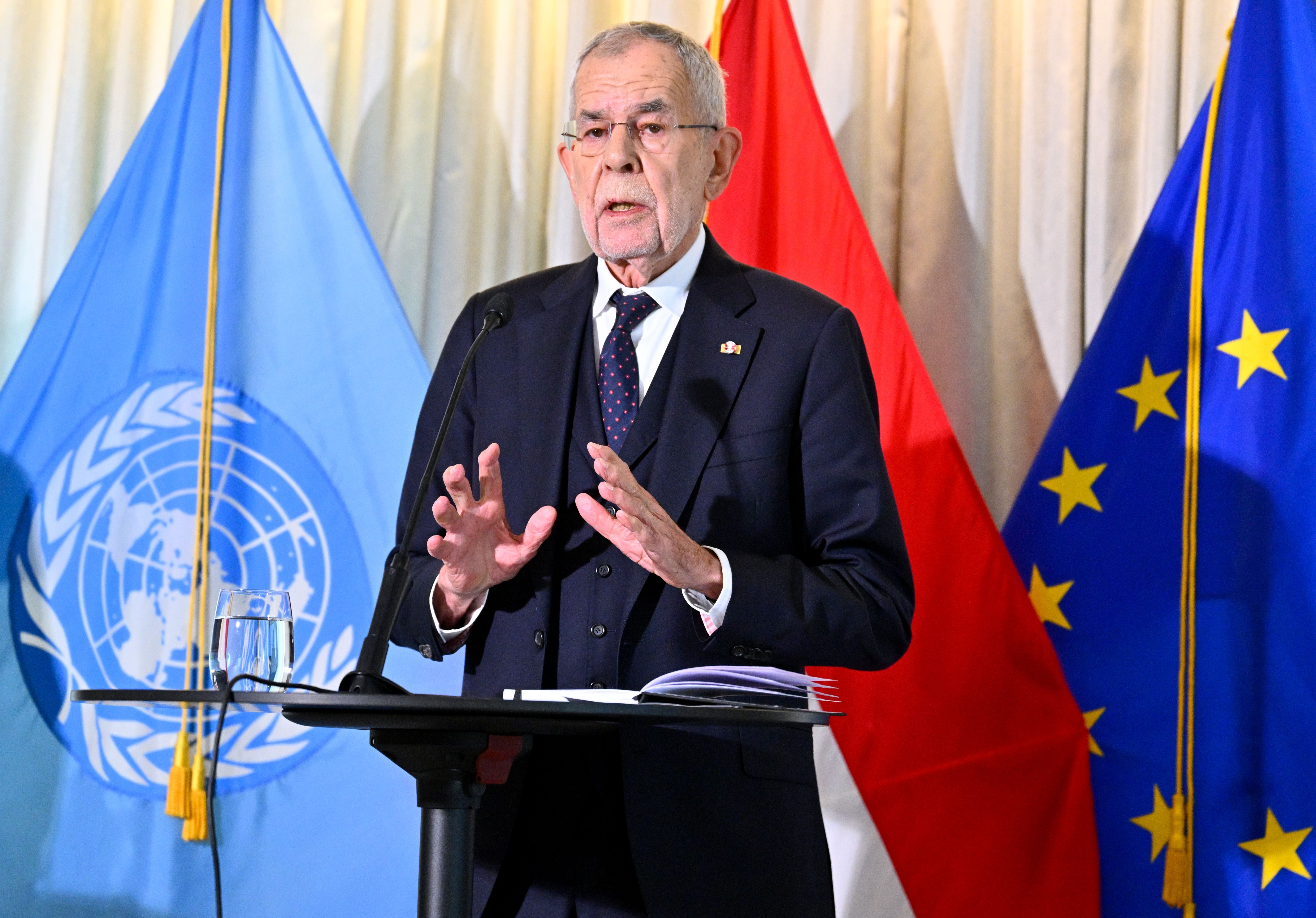 Ein Mann im Anzug spricht am Rednerpult vor UN-, Österreich- und EU-Flaggen.