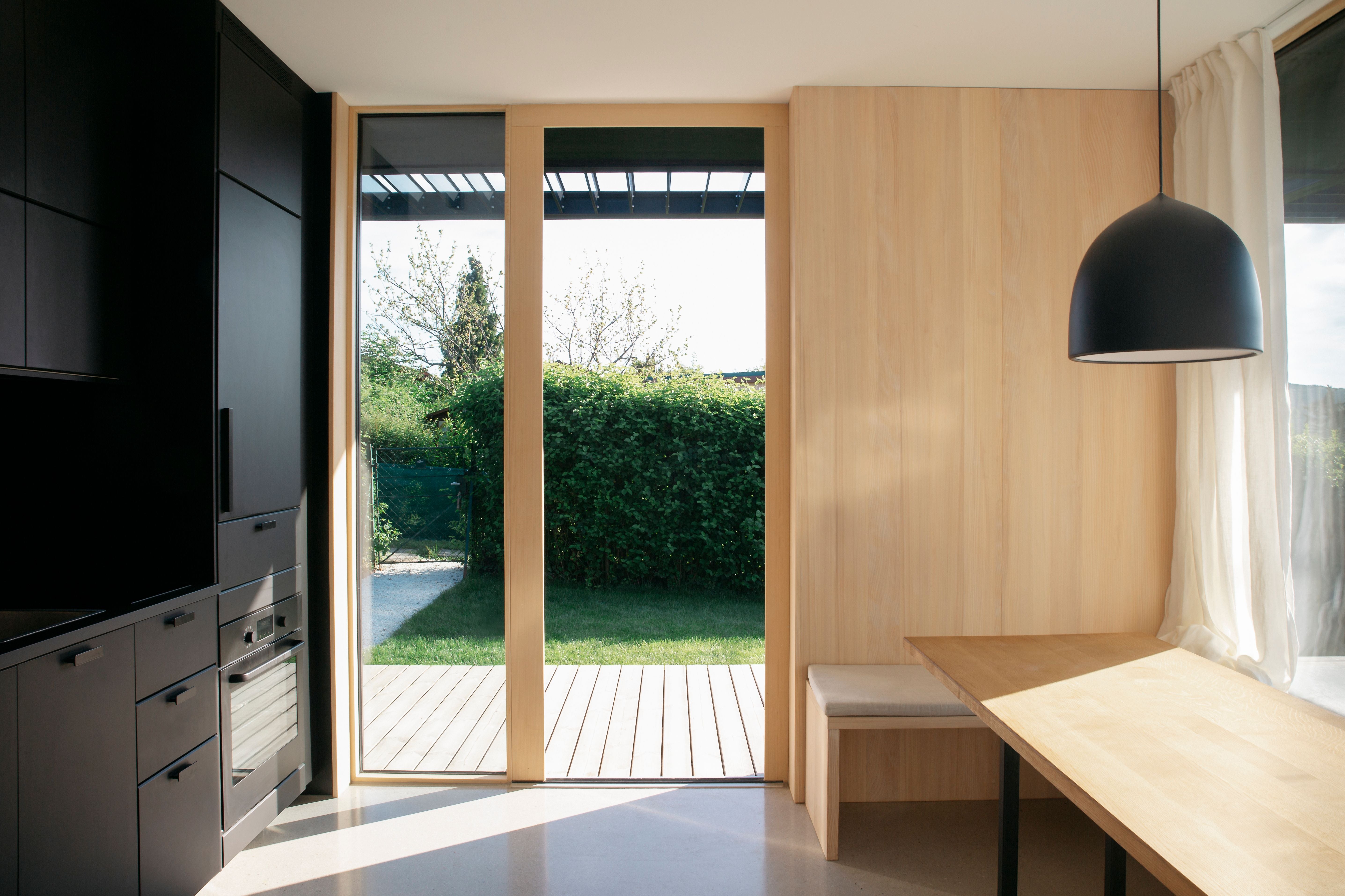 Modernes Tiny House mit Holzinterieur, großer Glas-Terrassentür und Blick ins Grüne.