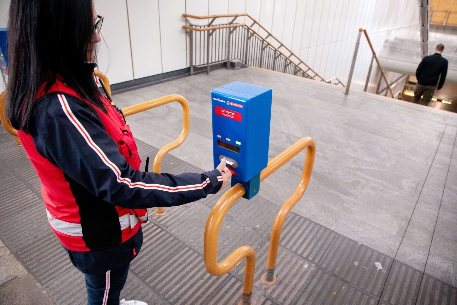 Frau entwertet ein Ticket an einem blauen Automaten in einer Wiener U-Bahn-Station.