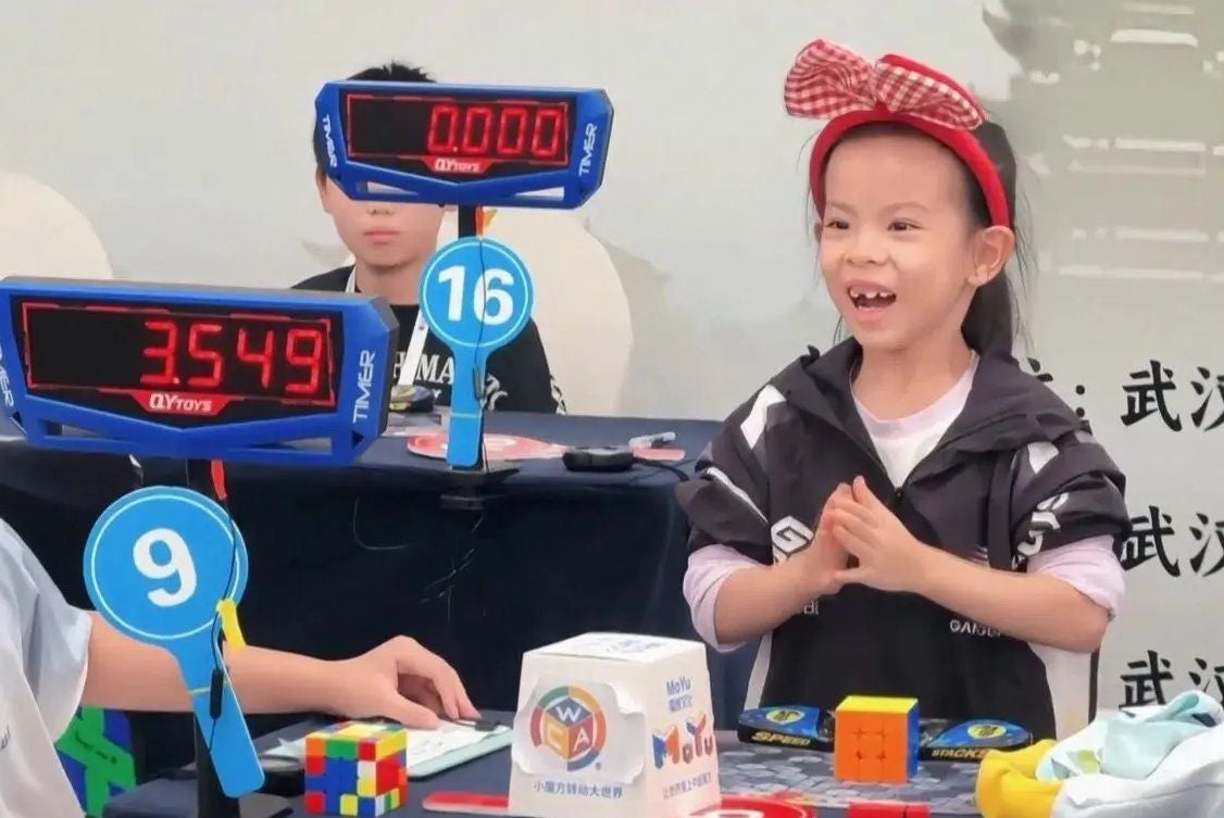 Ein Mädchen freut sich bei einem Speedcubing-Wettbewerb mit 3,549 Sekunden auf der Stoppuhr.