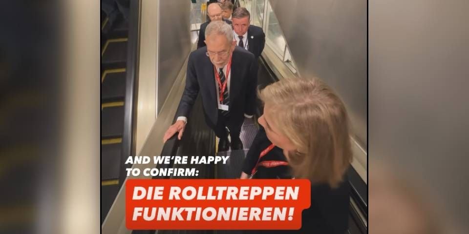 Mehrere Personen fahren gemeinsam auf einer Rolltreppe in einem Gebäude.