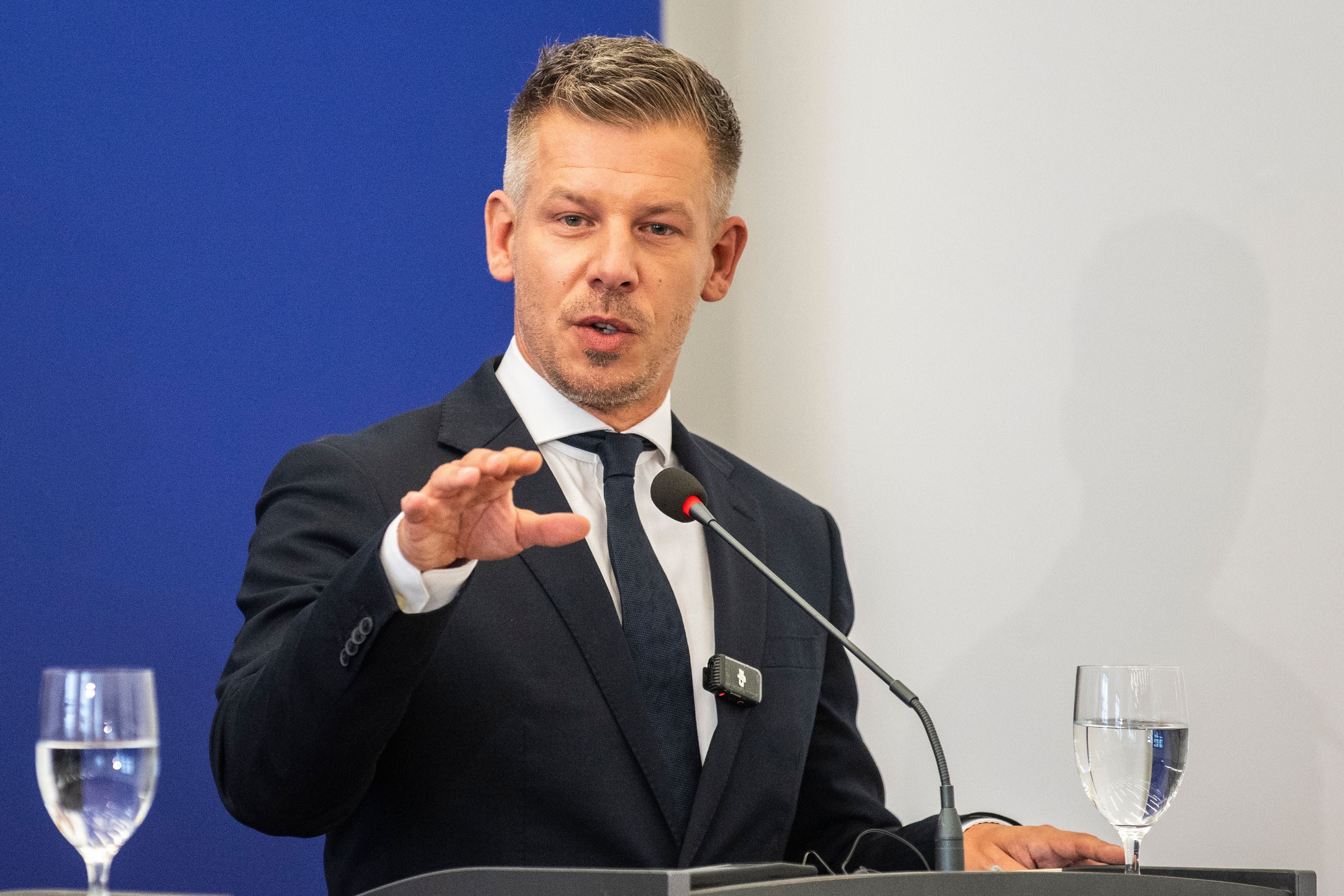 Ein Mann im Anzug spricht auf einer Pressekonferenz an einem Rednerpult mit Mikrofon.