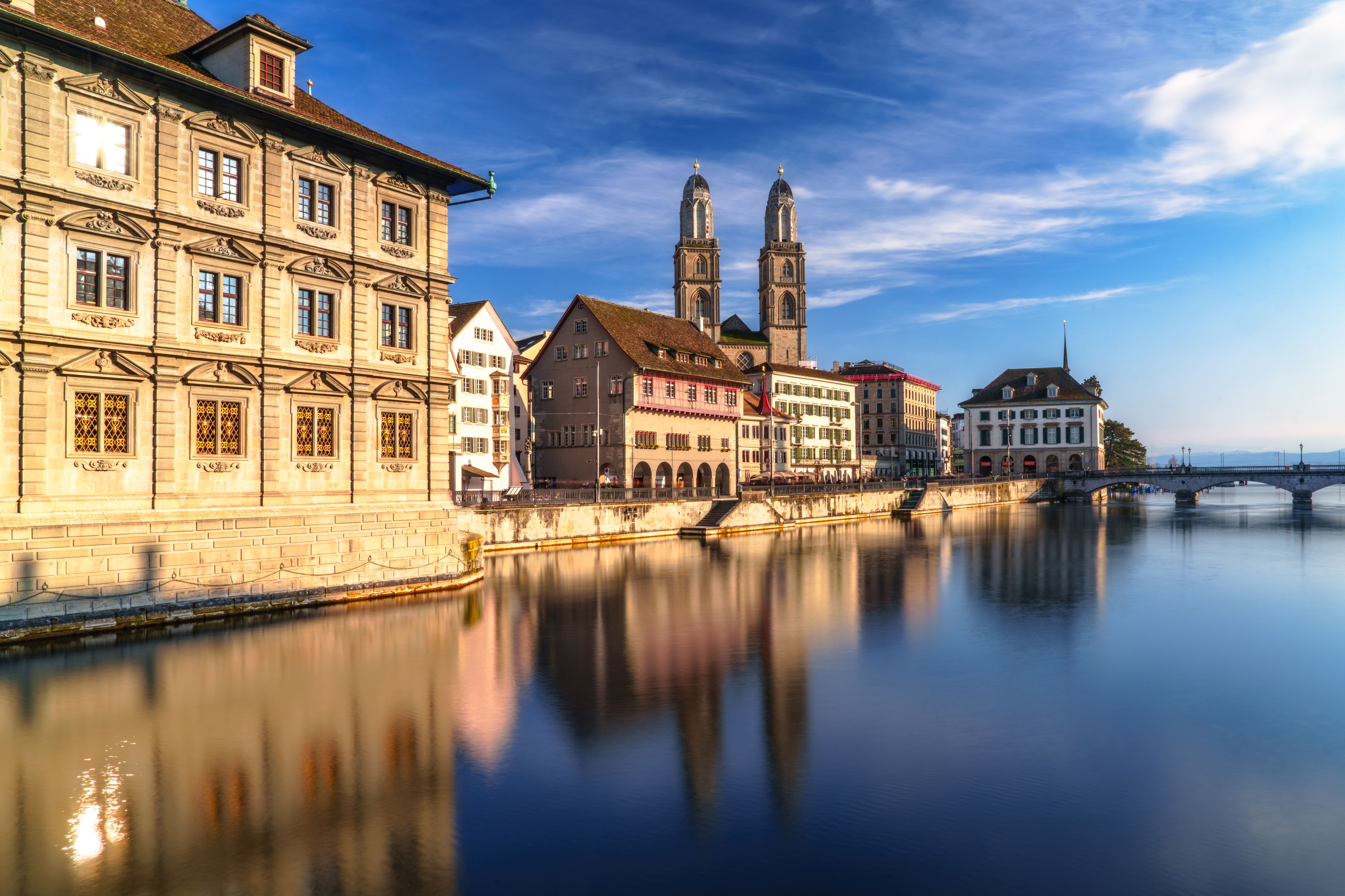 Historische Stadtansicht von Zürich spiegelt sich im Fluss Limmat bei blauem Himmel.