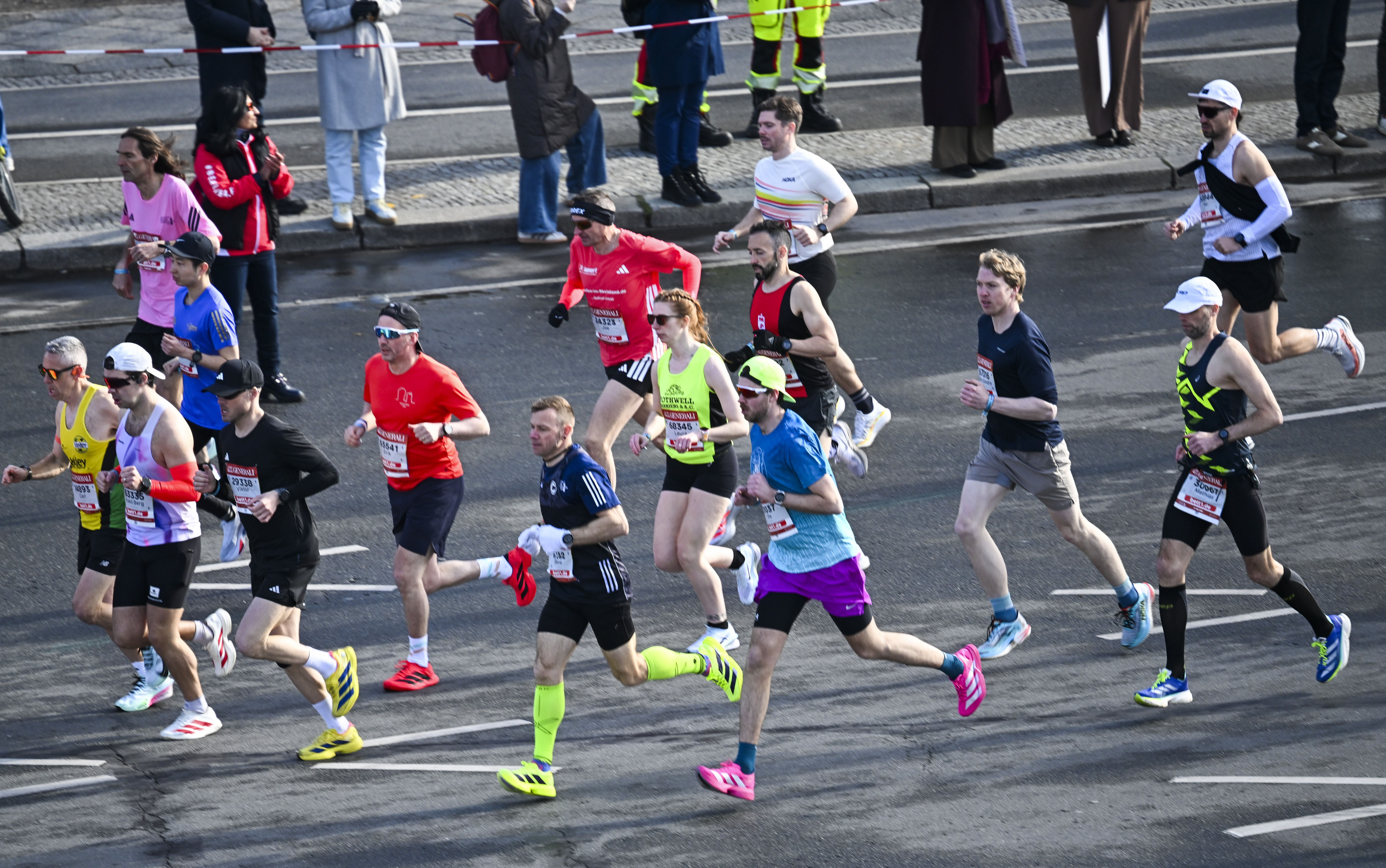 Mehrere Läufer nehmen am Generali Halbmarathon in Berlin auf einer abgesperrten Straße teil.