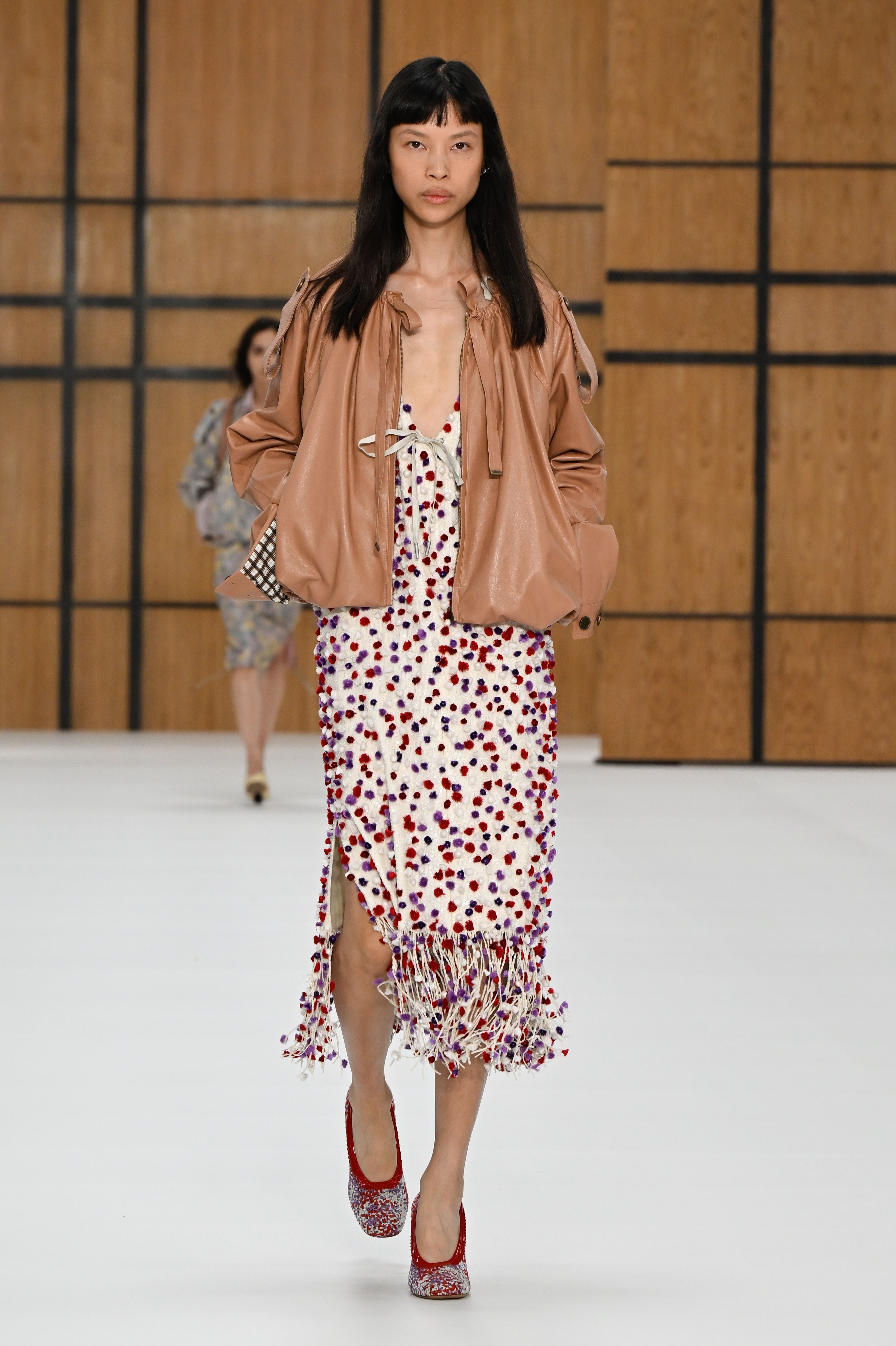 Model mit brauner Jacke und gemustertem Kleid auf dem Laufsteg der Burberry-Show in London.