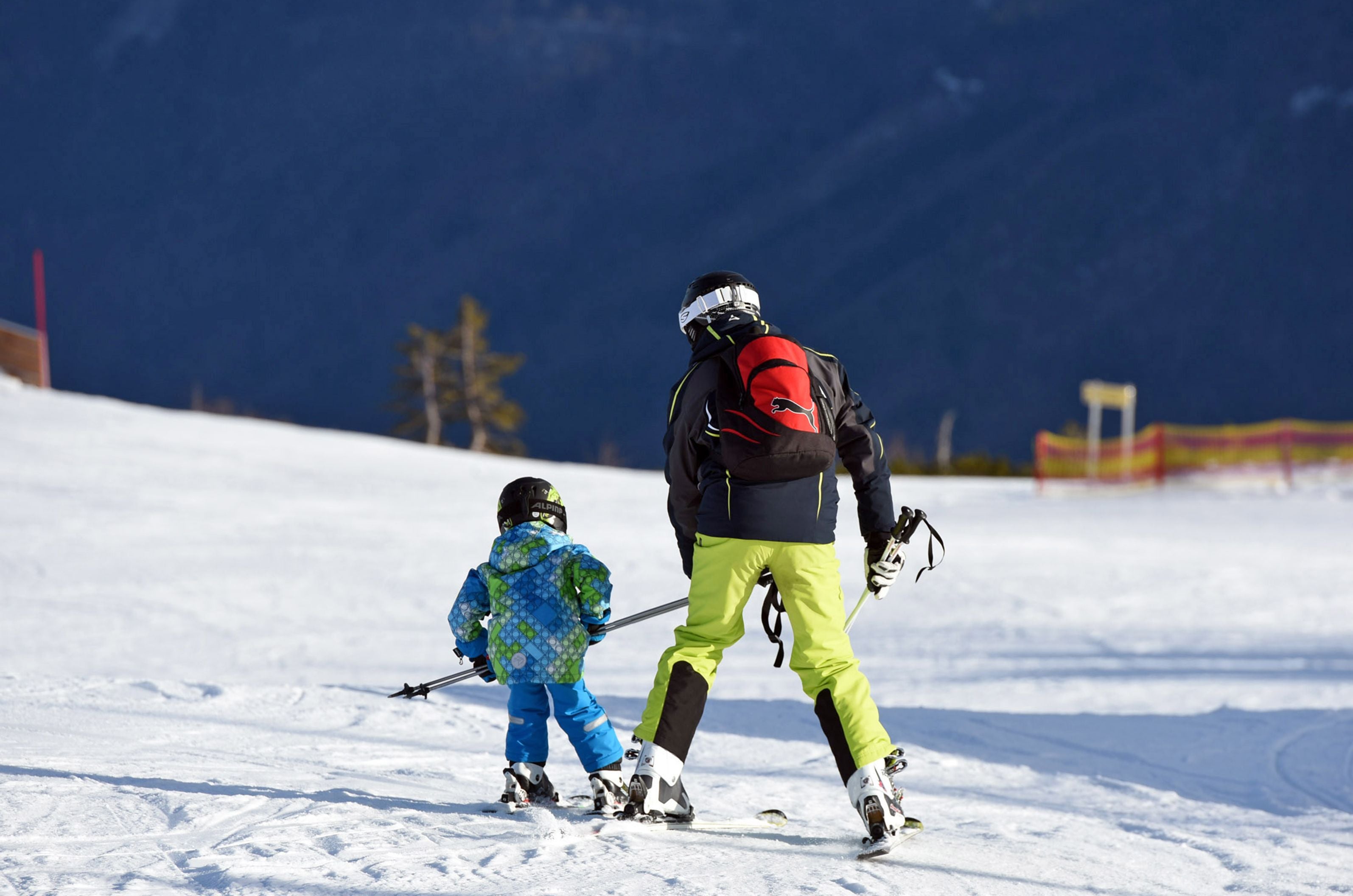 Ein Erwachsener und ein Kind fahren gemeinsam im Skigebiet Feuerkogel Ski.