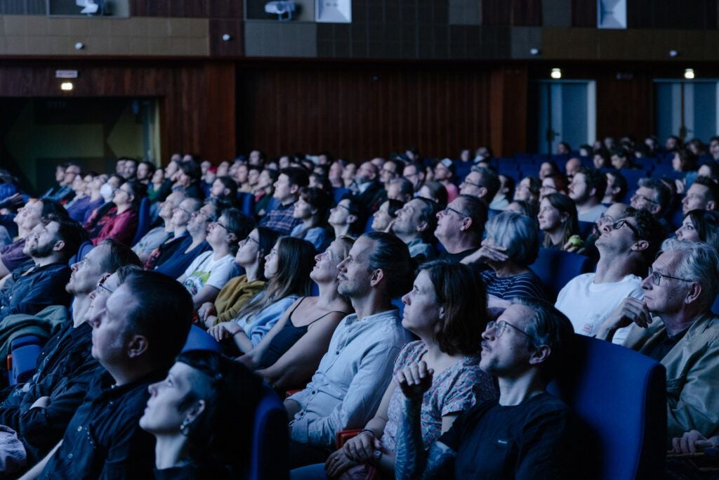 Viele Personen sitzen im Kino und schauen gespannt auf die Leinwand beim Slash Filmfestival.