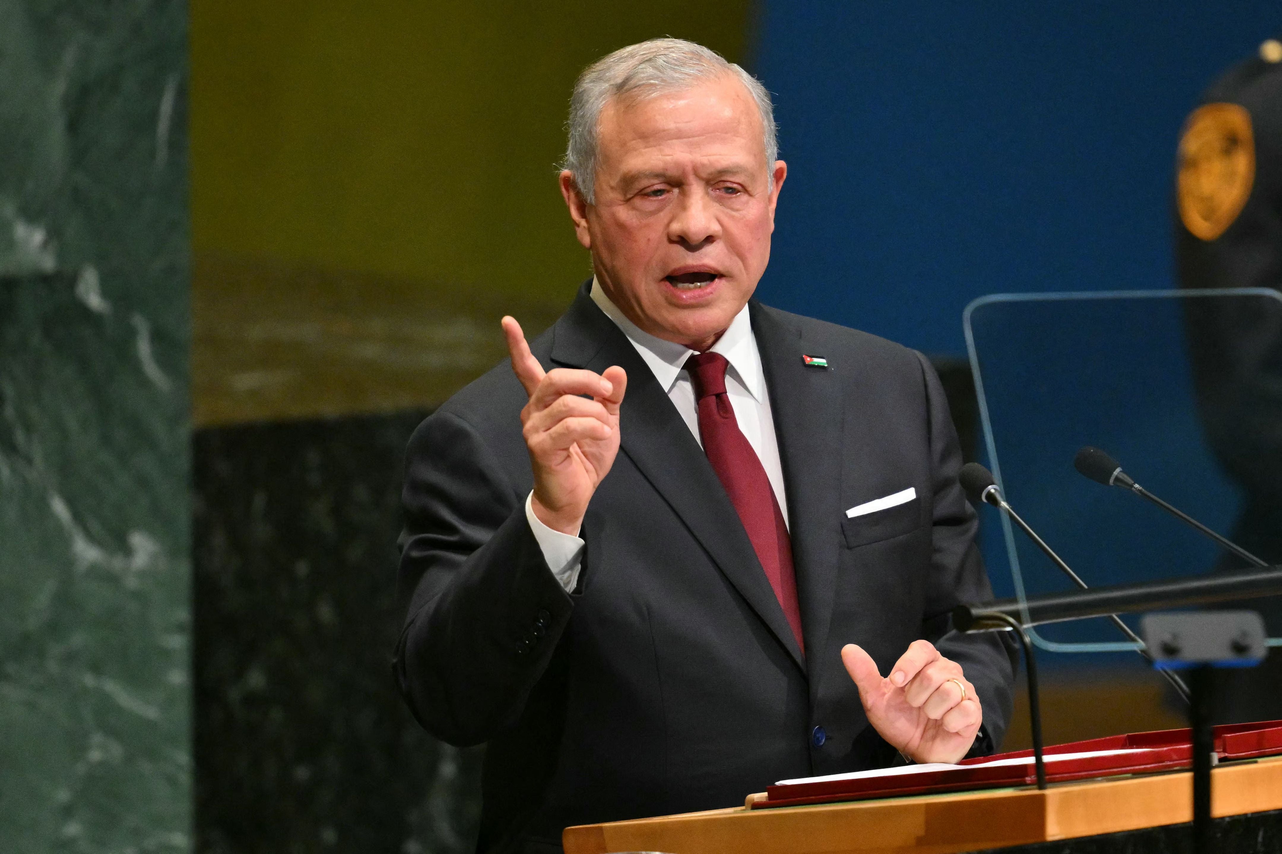 Ein Mann im Anzug spricht an einem Rednerpult mit Mikrofonen bei einer Konferenz.