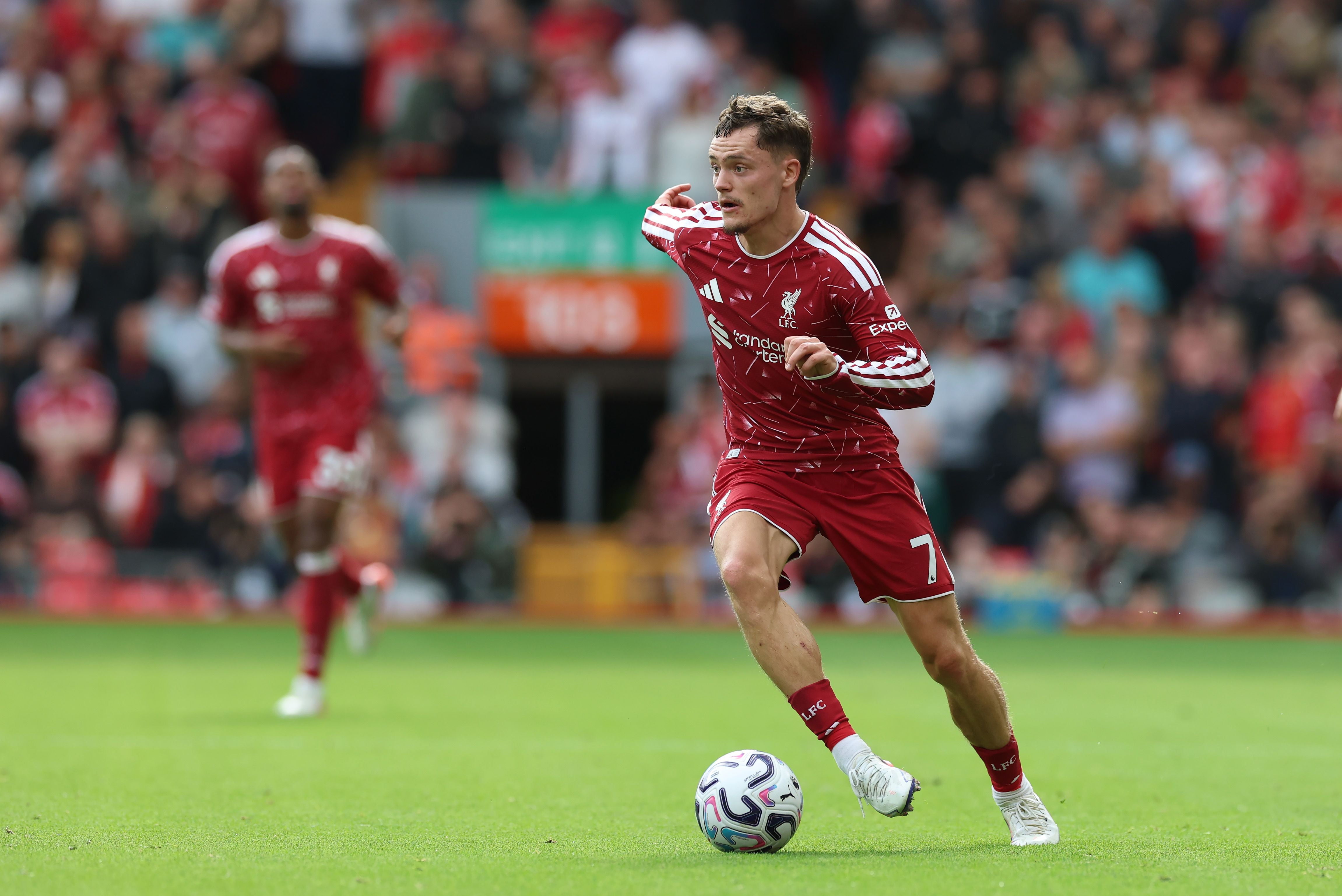 Ein Fußballspieler von Liverpool läuft mit dem Ball über das Spielfeld, im Hintergrund Zuschauer.