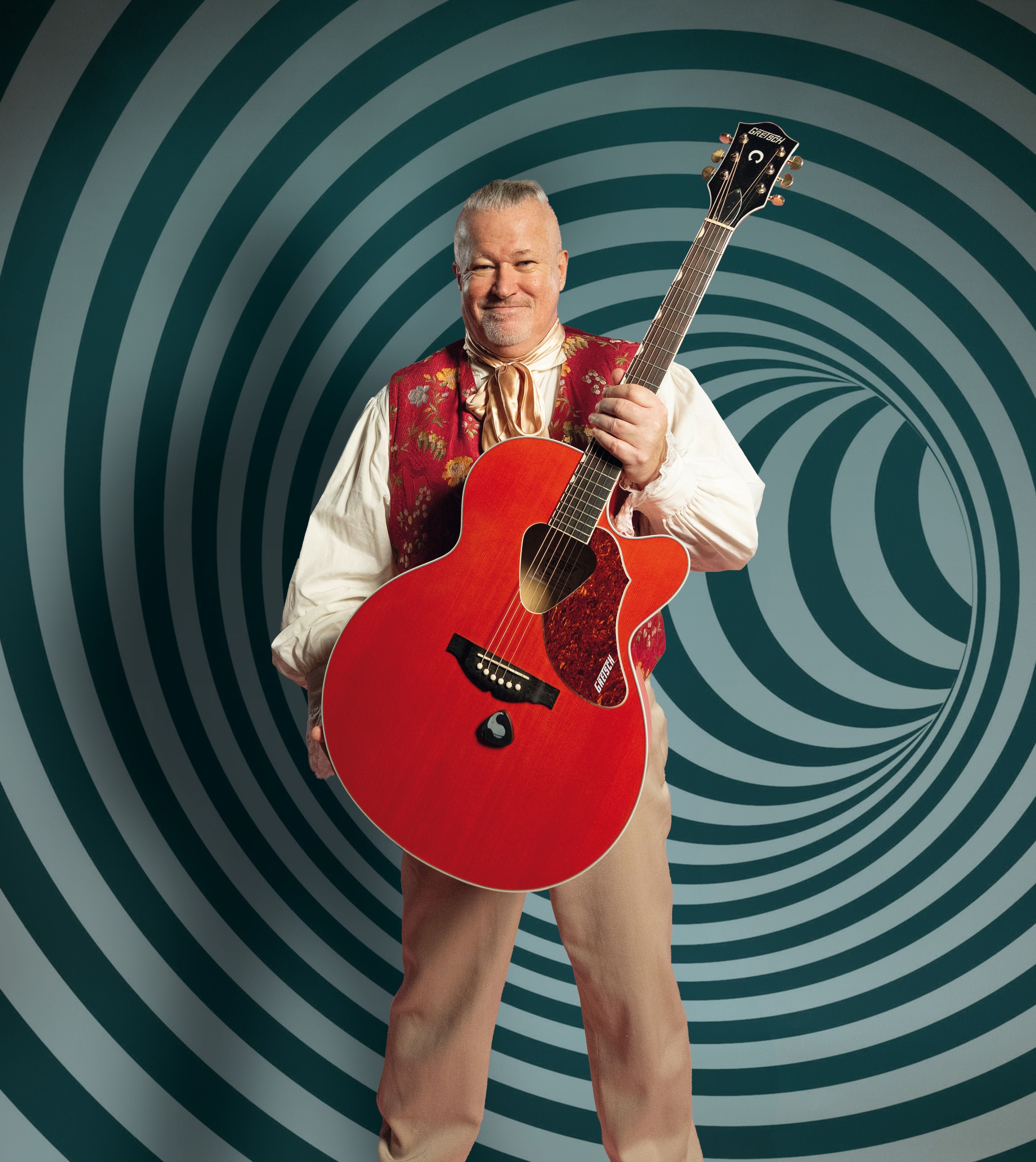 Ein Mann im Trachtenhemd hält eine rote Akustikgitarre vor spiralförmigem Hintergrund.