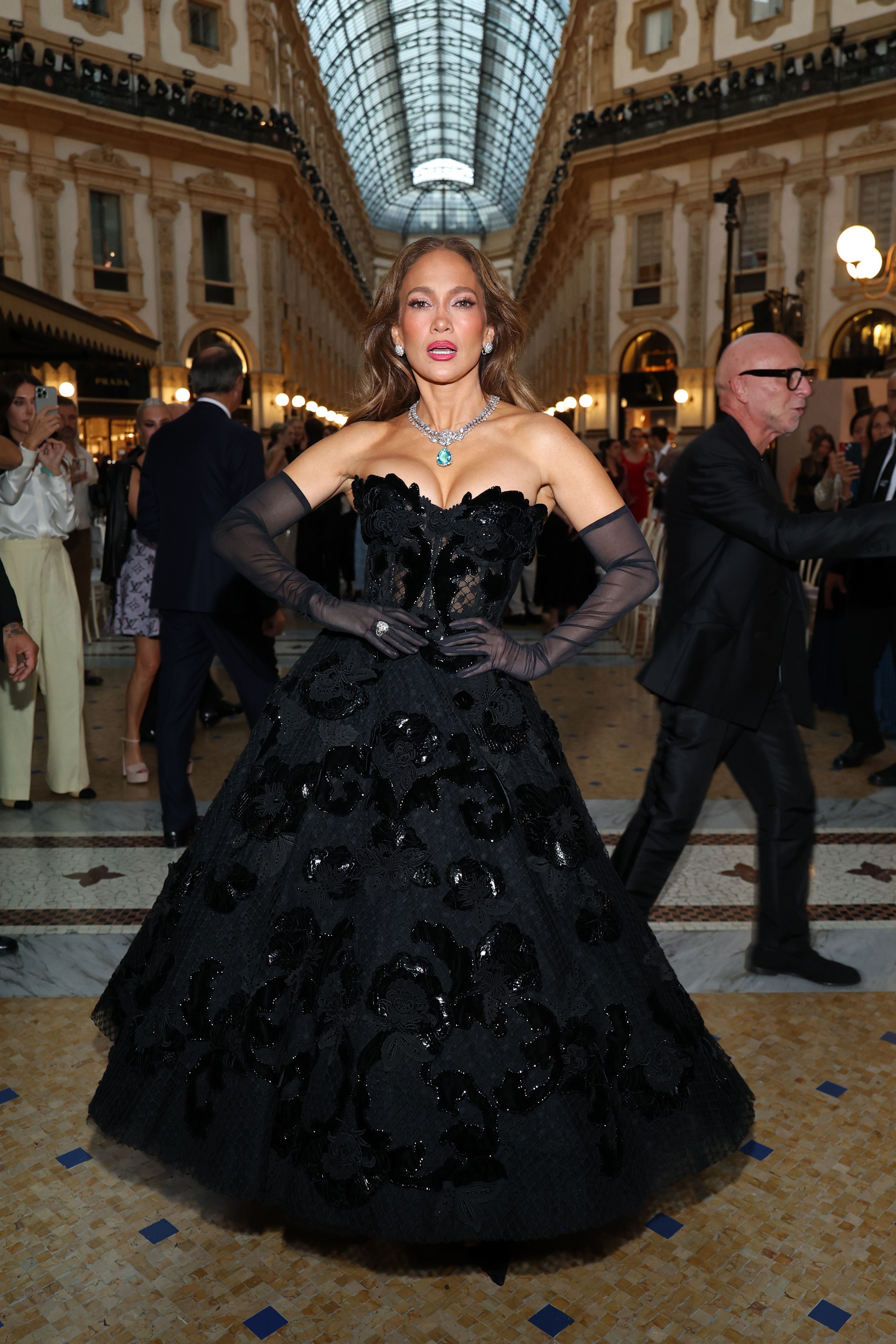 Frau in eleganter schwarzer Abendrobe steht in einer prunkvollen Galerie in Mailand.