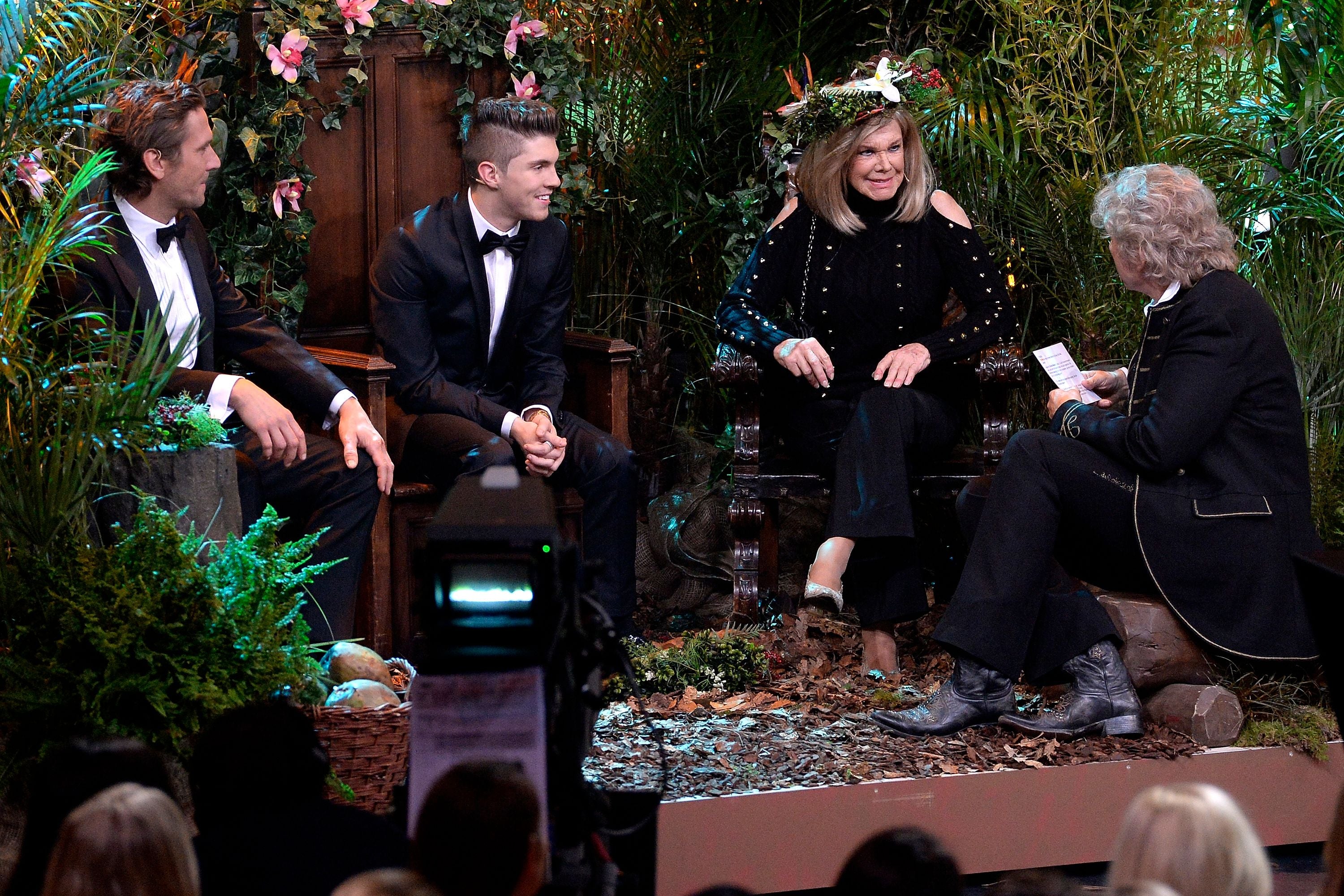 Vier elegant gekleidete Personen sitzen in einem Dschungel-Set und unterhalten sich bei einer TV-Show.
