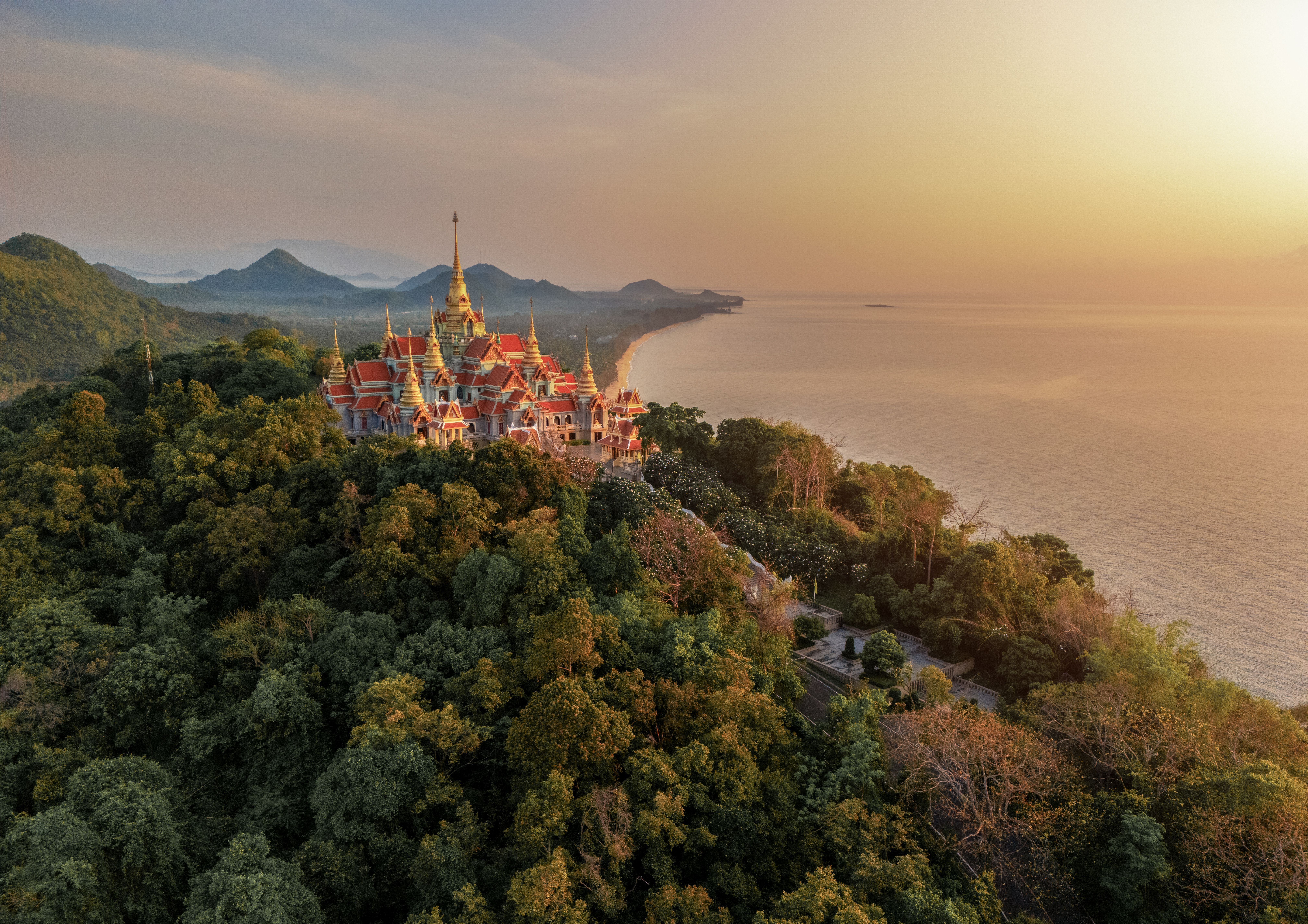 Tempel Phra Mahathat Chedi Phakdi Prakat auf einem Hügel mit Blick aufs Meer bei Sonnenuntergang.