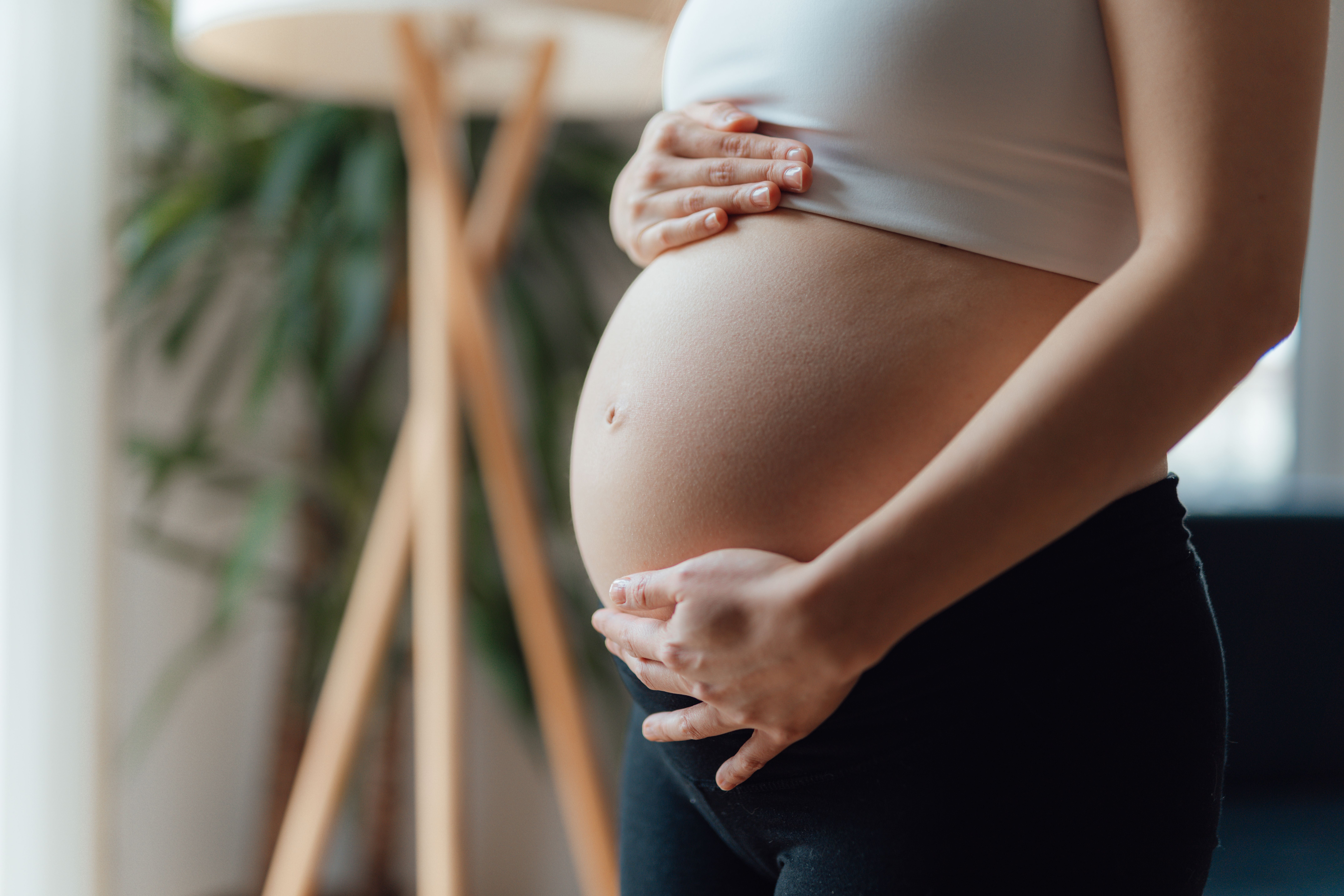 Schwangere Frau hält ihren Bauch, Nahaufnahme von der Seite.